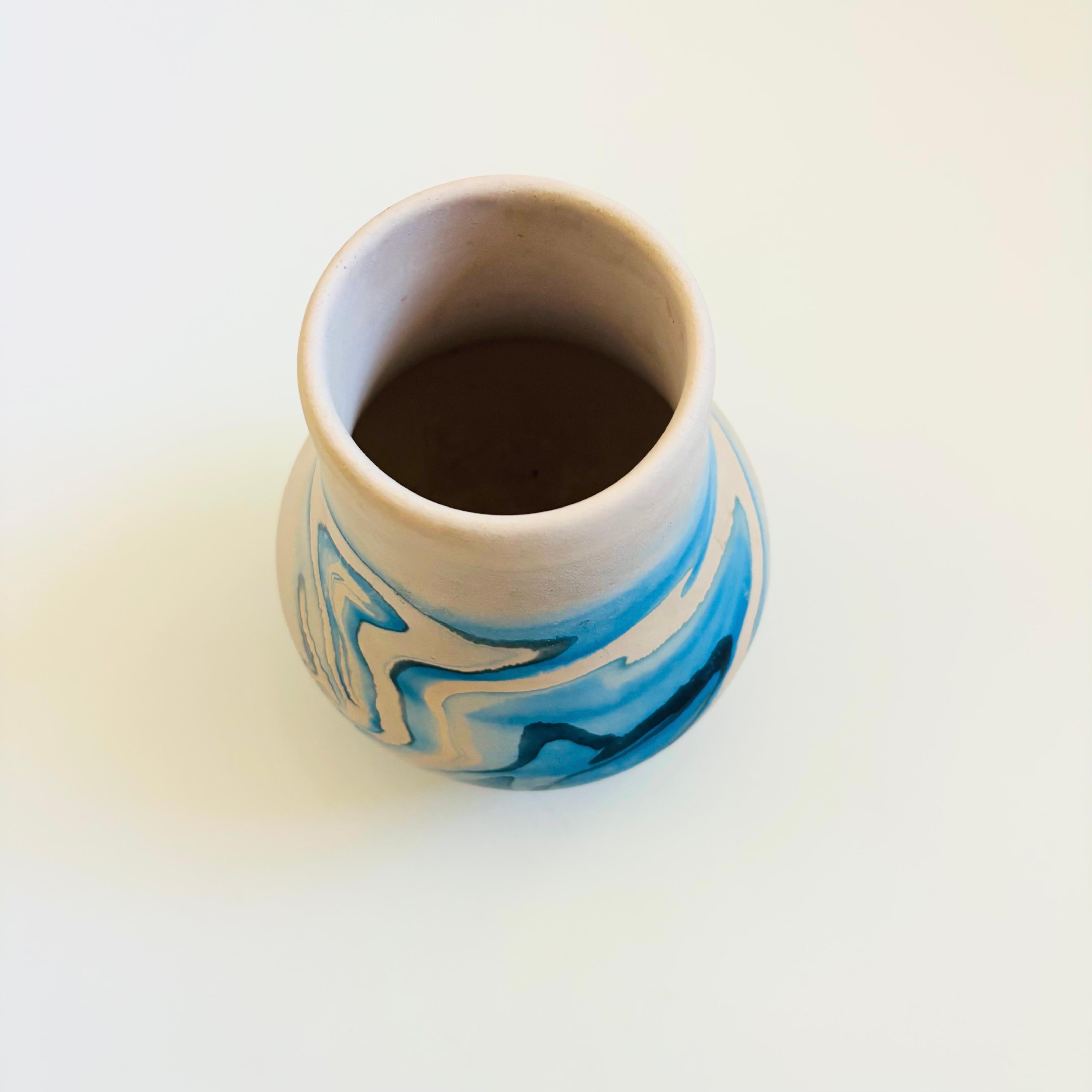 Un vaso vintage in ceramica nemadji con un bellissimo motivo organico di volute blu su uno sfondo bianco chiaro. Esterno smaltato opaco. Interno non smaltato solo per scopi decorativi o per composizioni di fiori secchi. Marcato sulla base.

