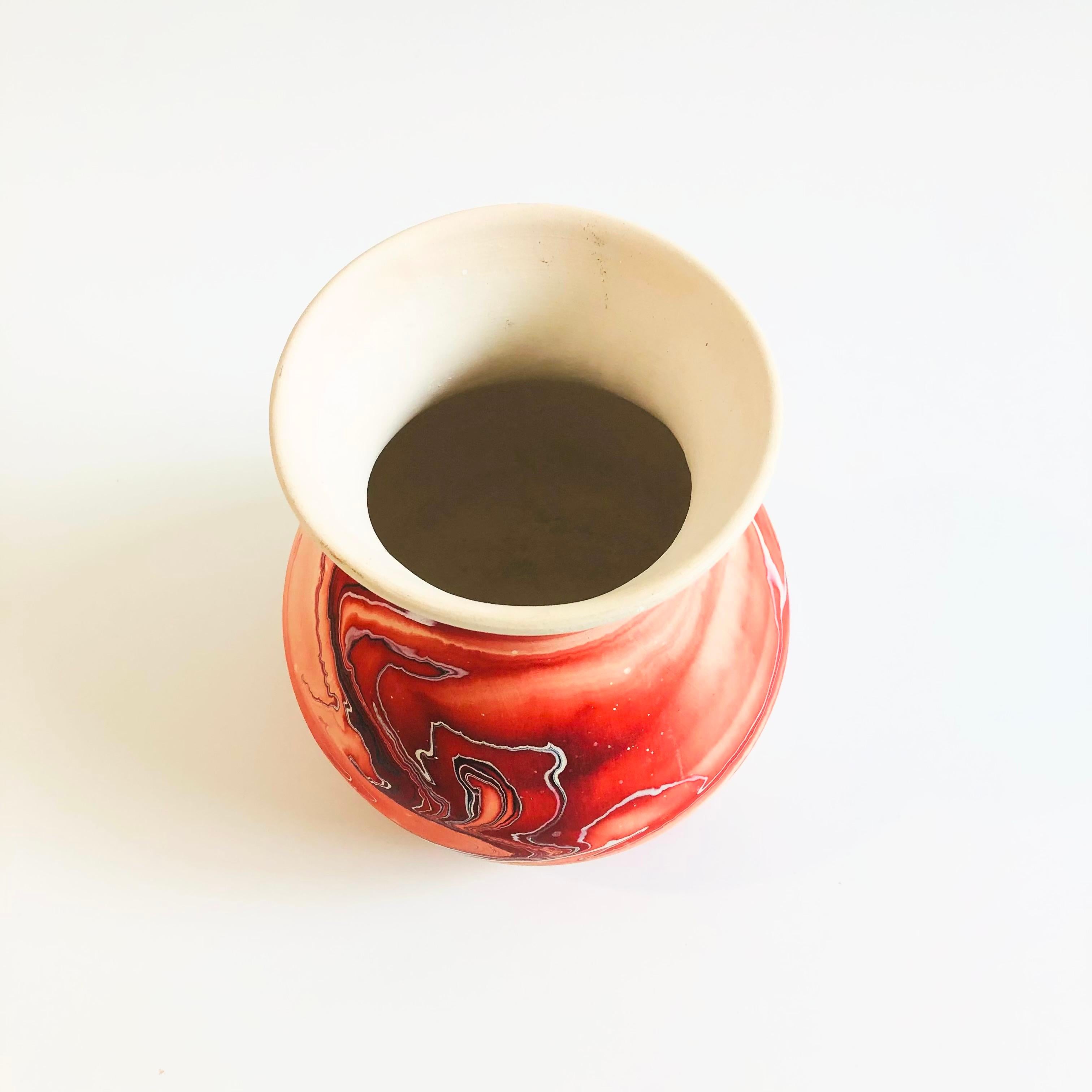 A vintage nemadji pottery vase with a beautiful organic pattern of vibrant red swirls on a light off-white background, matte glaze. Unglazed interior for decorative purposes or dried flower arrangements only. Marked on the base.

