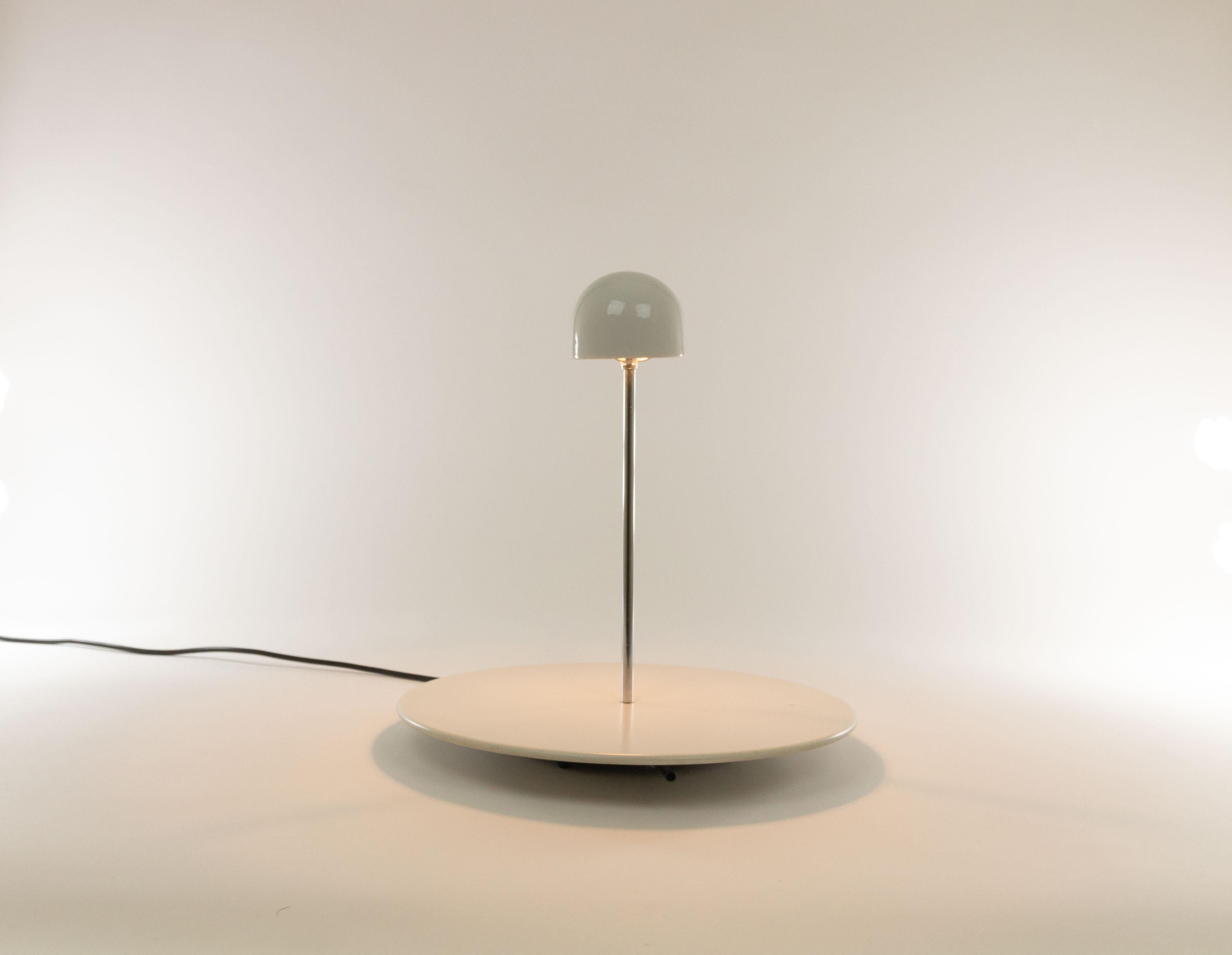 Nemea table lamp by Vico Magistretti and produced by Artemide.

Magistretti designed Nemea in 1979. It consists of a round base, with a chrome tube and a hemisphere mounted on it. The halogen lamp is incorporated in this hemisphere; the light