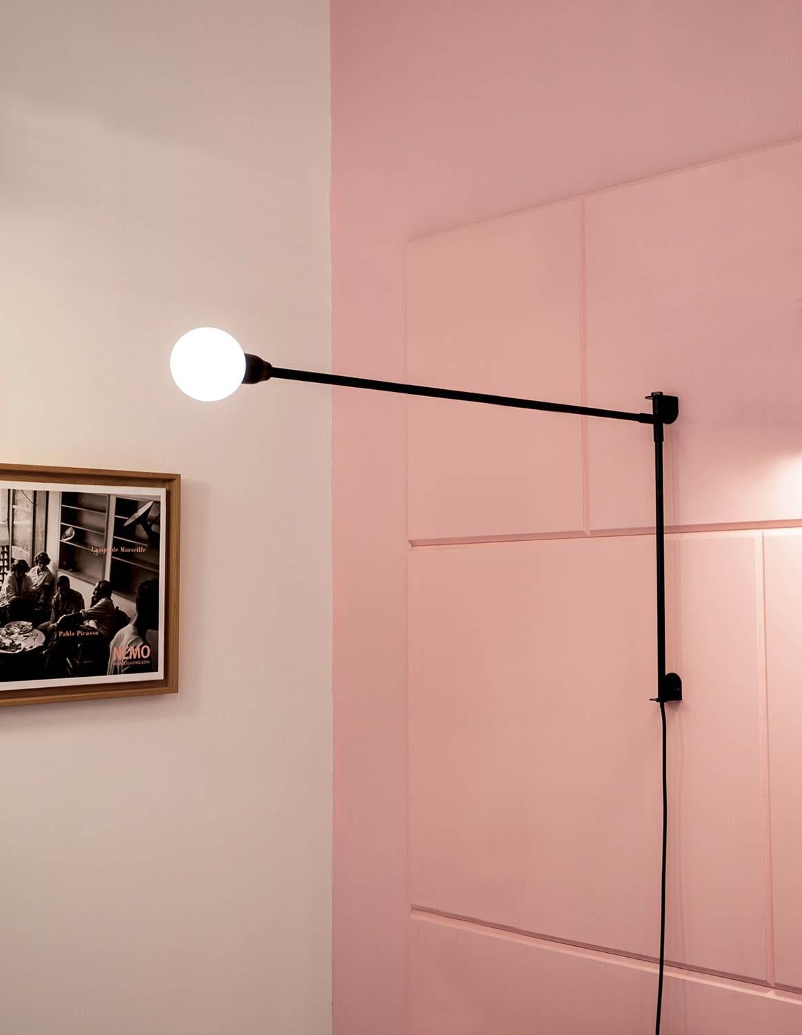 Aplique en relieve inspirado en la botavara de los veleros. En aluminio y metal pintado de negro mate, también disponible en versión Mini de dimensiones reducidas. El brazo está fijado a la pared y gira sobre el eje horizontal, formando un ángulo de