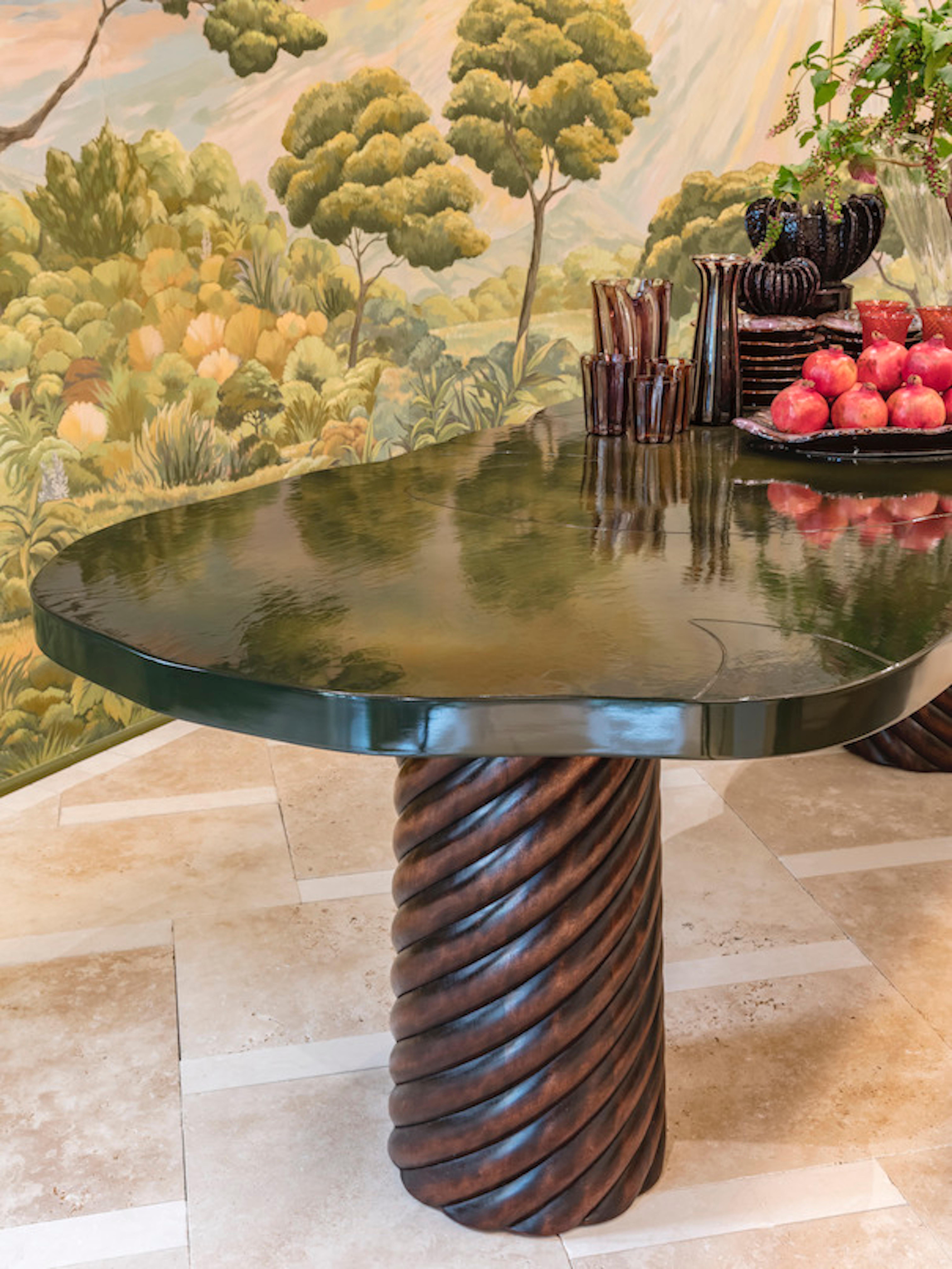 Table de salle à manger avec un plateau inspiré de la forme des nénuphars en laque vert nuancé, et des pieds en bois tordus. Pièce unique fabriquée en France.