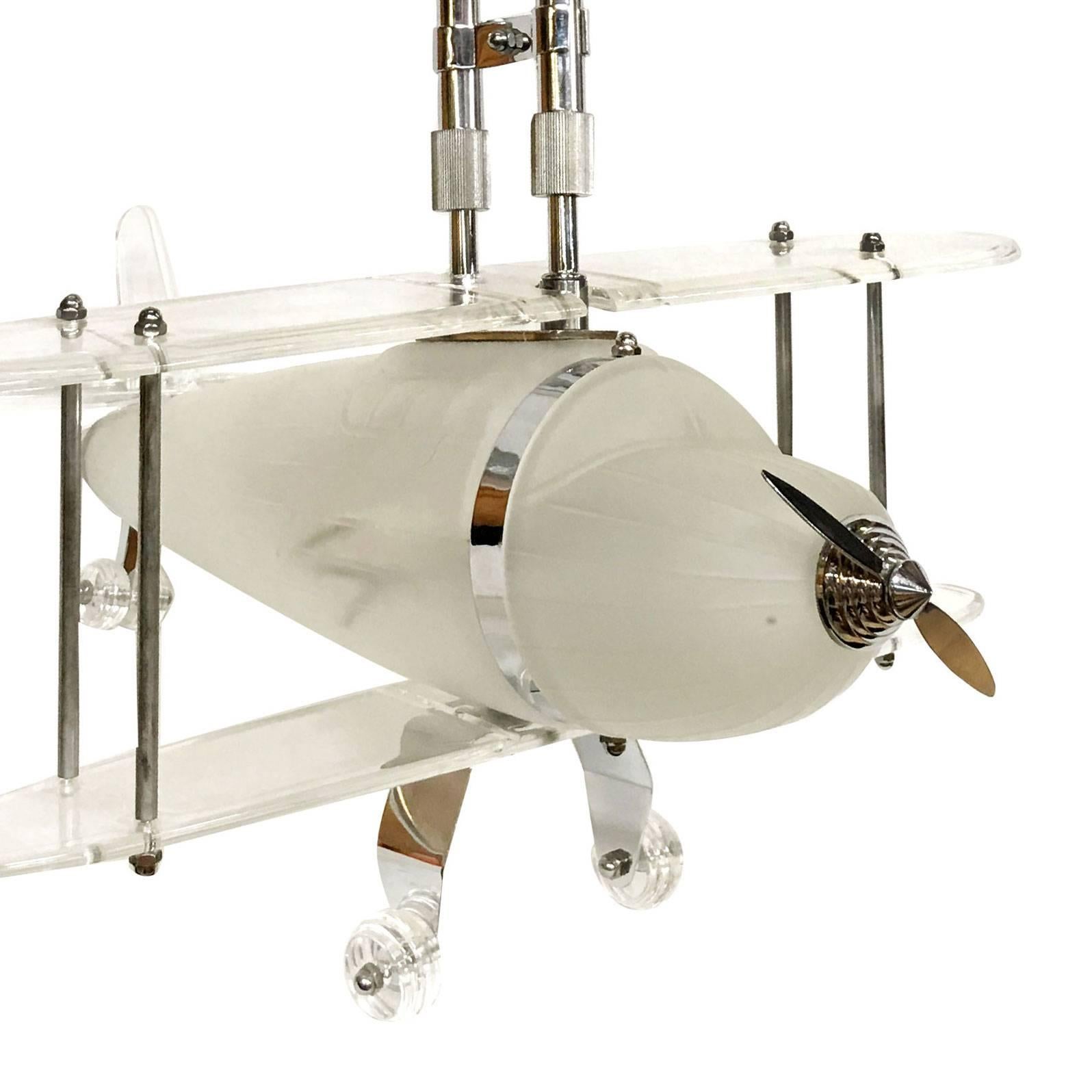 Rare polished chrome and acrylic biplane and airplane ceiling lamp chandelier. The model is constructed of a frosted glass body with acrylic wing and chrome accents aluminum body with an adjustable chrome post.

Measures: The height is just from