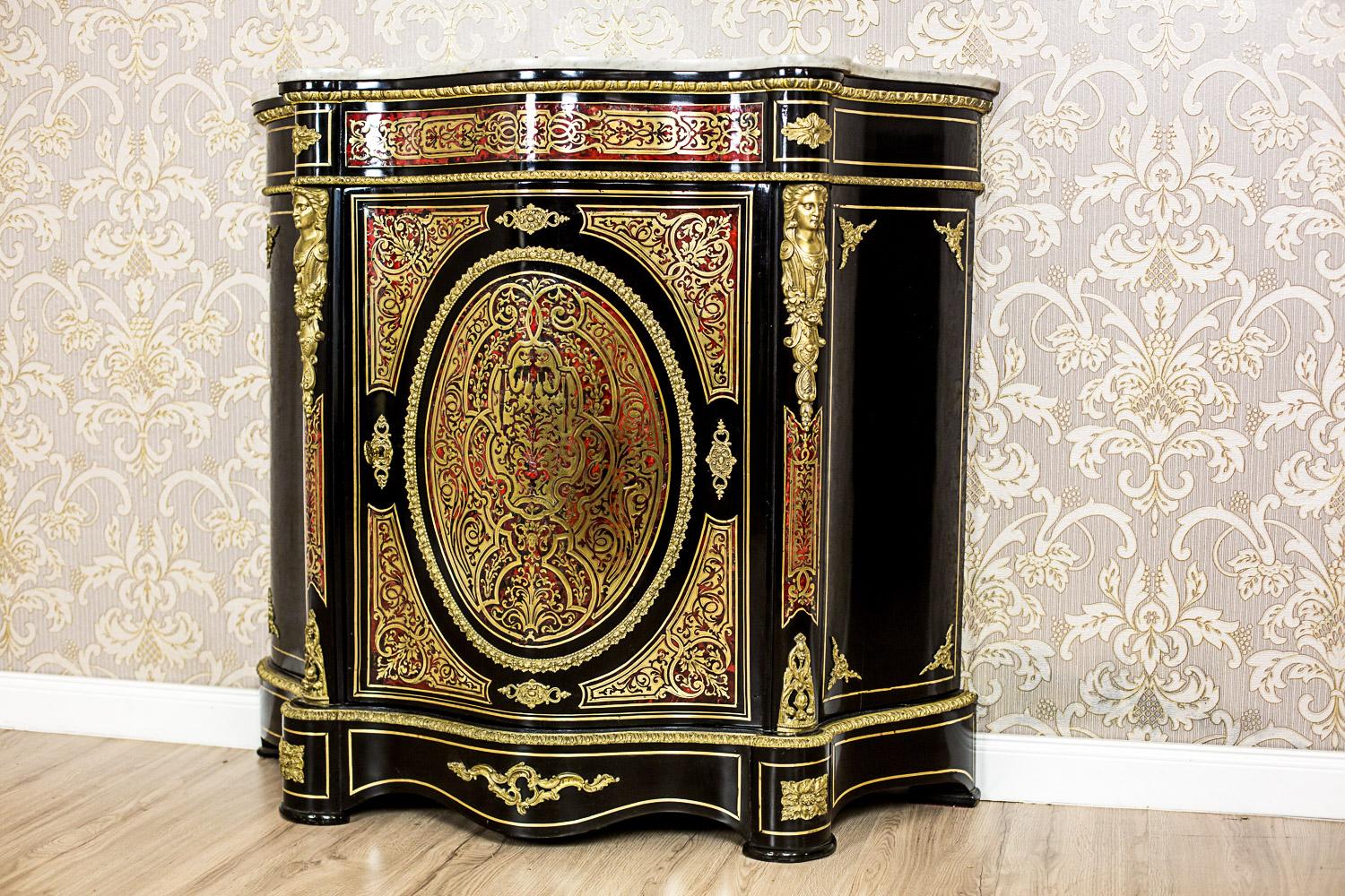 We present you this commode manufactured in the 19th century, in France, modeled on the 17th-century, Baroque furniture of the French ebéniste, A. Ch. Boulle. This piece of furniture is single-door, with sides that are set at the angle of 45 degrees