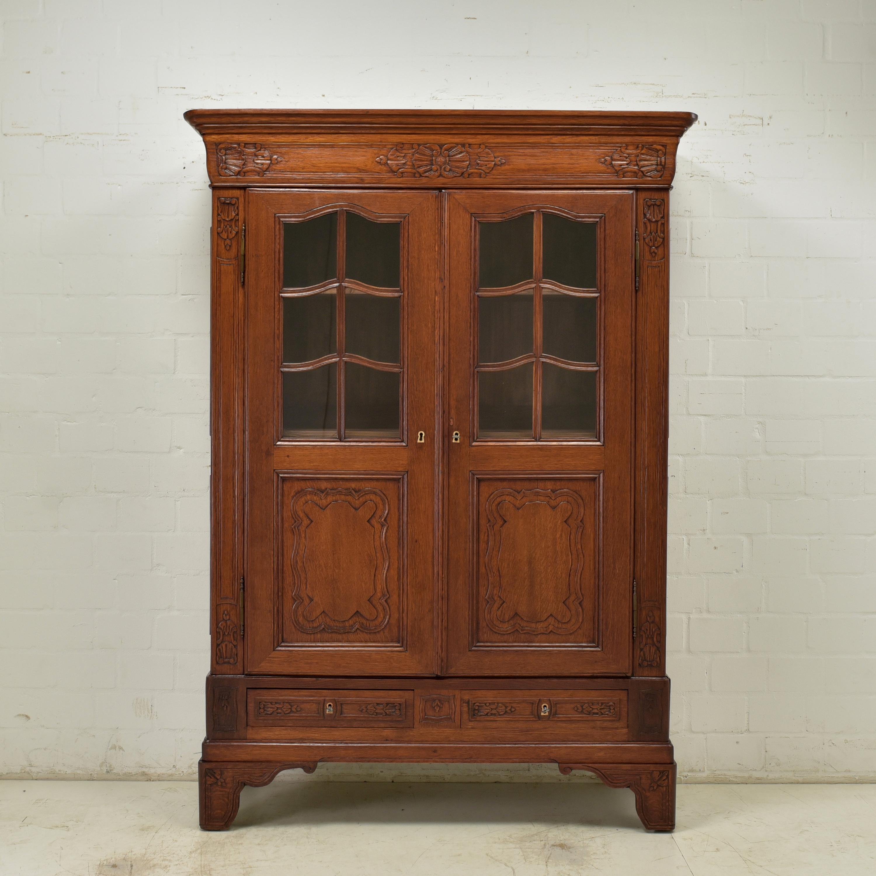 Display cabinet restored neo-baroque late Biedermeier around 1860 oak

Features:
Solid oak body, solid softwood inside
Two-door model with three shelves and two drawers
High quality
Beautiful carved decor
Beautiful patina
The cabinet can be