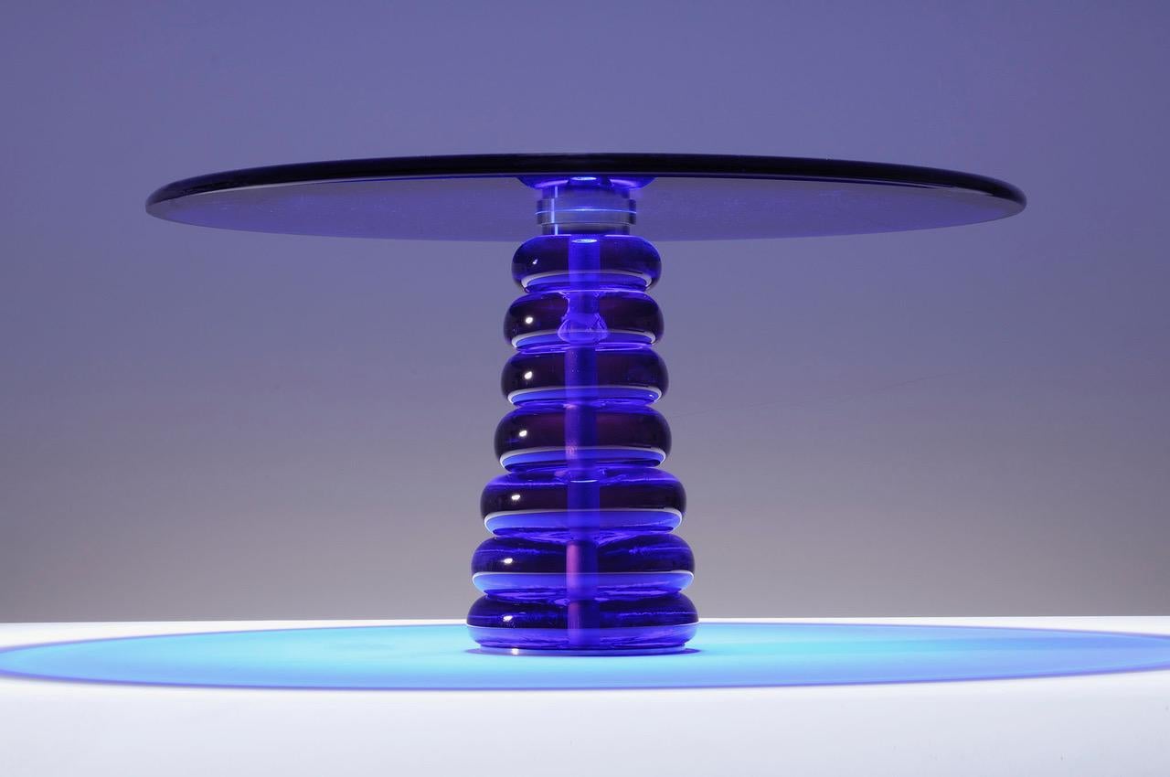 Plateau de table en verre coulé et coulé bleu cobalt, sur base en verre lobé améthyste Neoydmium, reliée par une monture à collier en acier.
Gravé 
