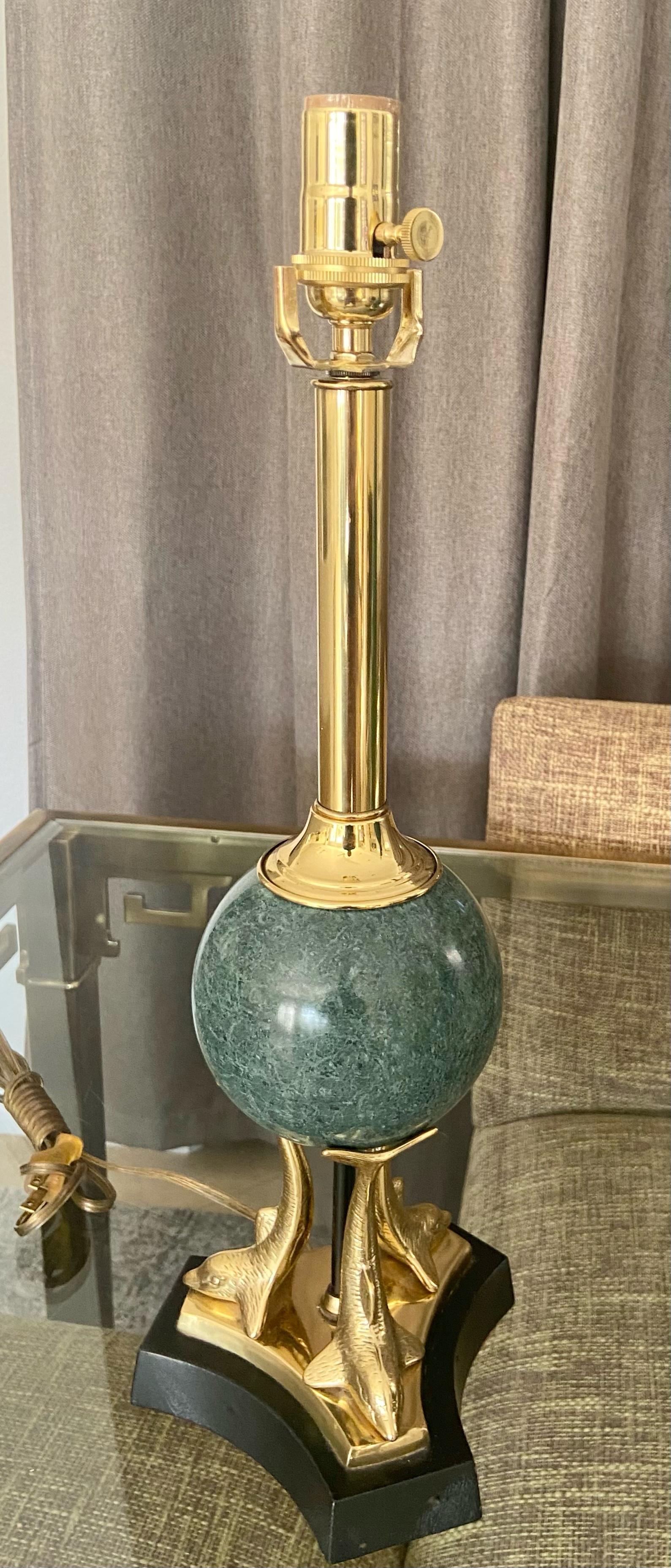 Neoclassical style brass dolphin motif and marble table or desk lamp. Nicely chased detailing on brass dolphins, center portion solid round green marble, resting on black leather wrapped base. Newly wired for use in U.S, including new cord and 3 way