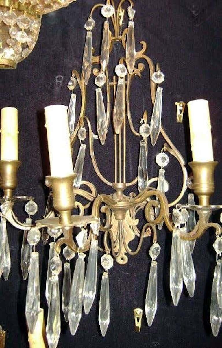 A pair of Swedish three-light patinated bronze sconces with lyre shaped body and with crystal pendants. 
Measurements:
Height: 18 in.
Depth: 7.5 in.
Width: 12 in.