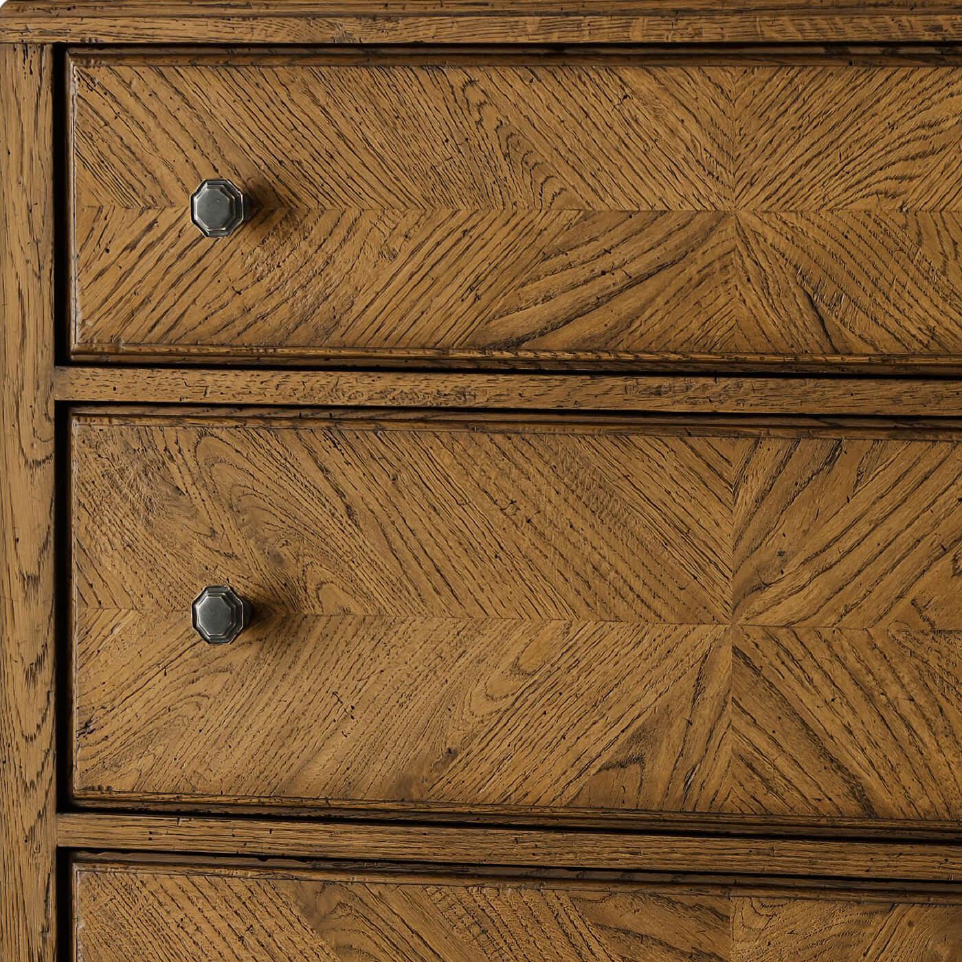 A neo classic style dark oak parquetry tall chest of drawers with mirrored herringbone oak parquetry including five deep drawers accented with Verde Bronze finished handles on tapered oak legs in our dusk finish.

Dimensions: 36