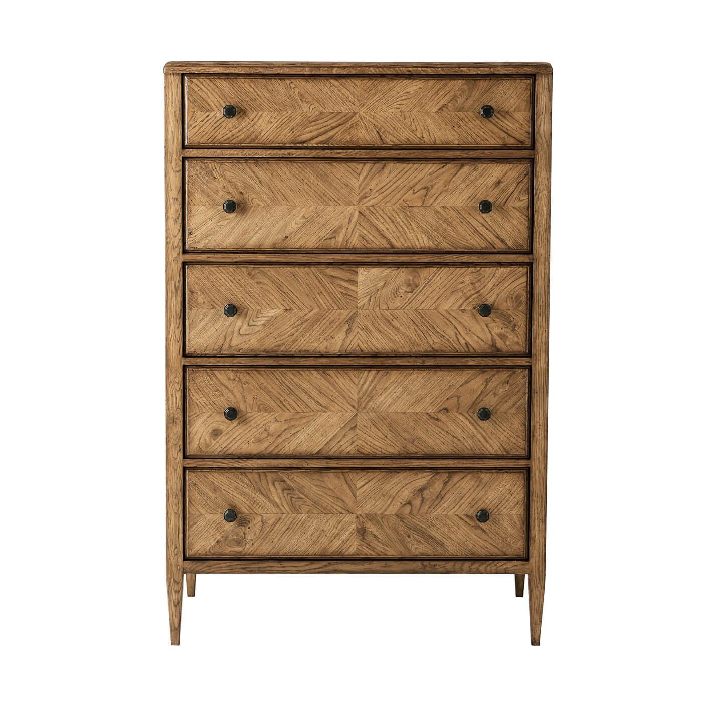 A neo cassic style oak parquetry tall chest of drawers with mirrored herringbone oak parquetry including five deep drawers accented with Verde Bronze finished handles on tapered oak legs in our Dwan finish.

Dimensions: 36