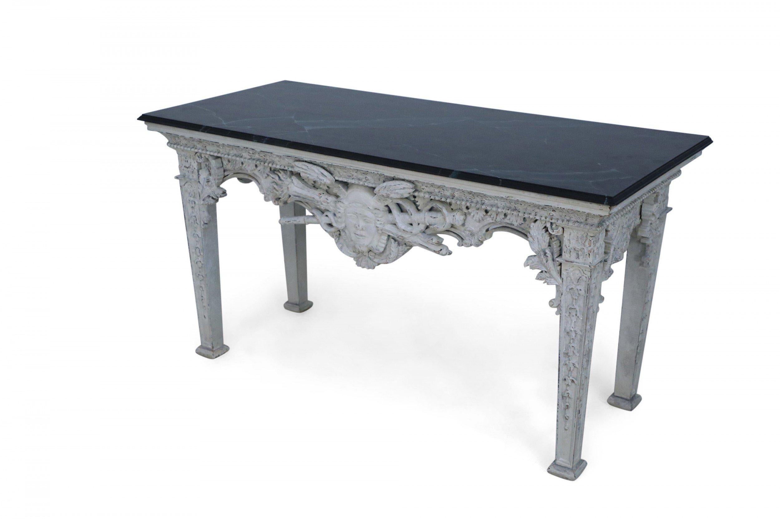 Italian neo-classic-style (modern) rectangular console table combining a white-painted, distressed base carved with a central face sitting above a torch crossed with a caduceus at the front apron, carved legs and a smooth painted faux marble top in