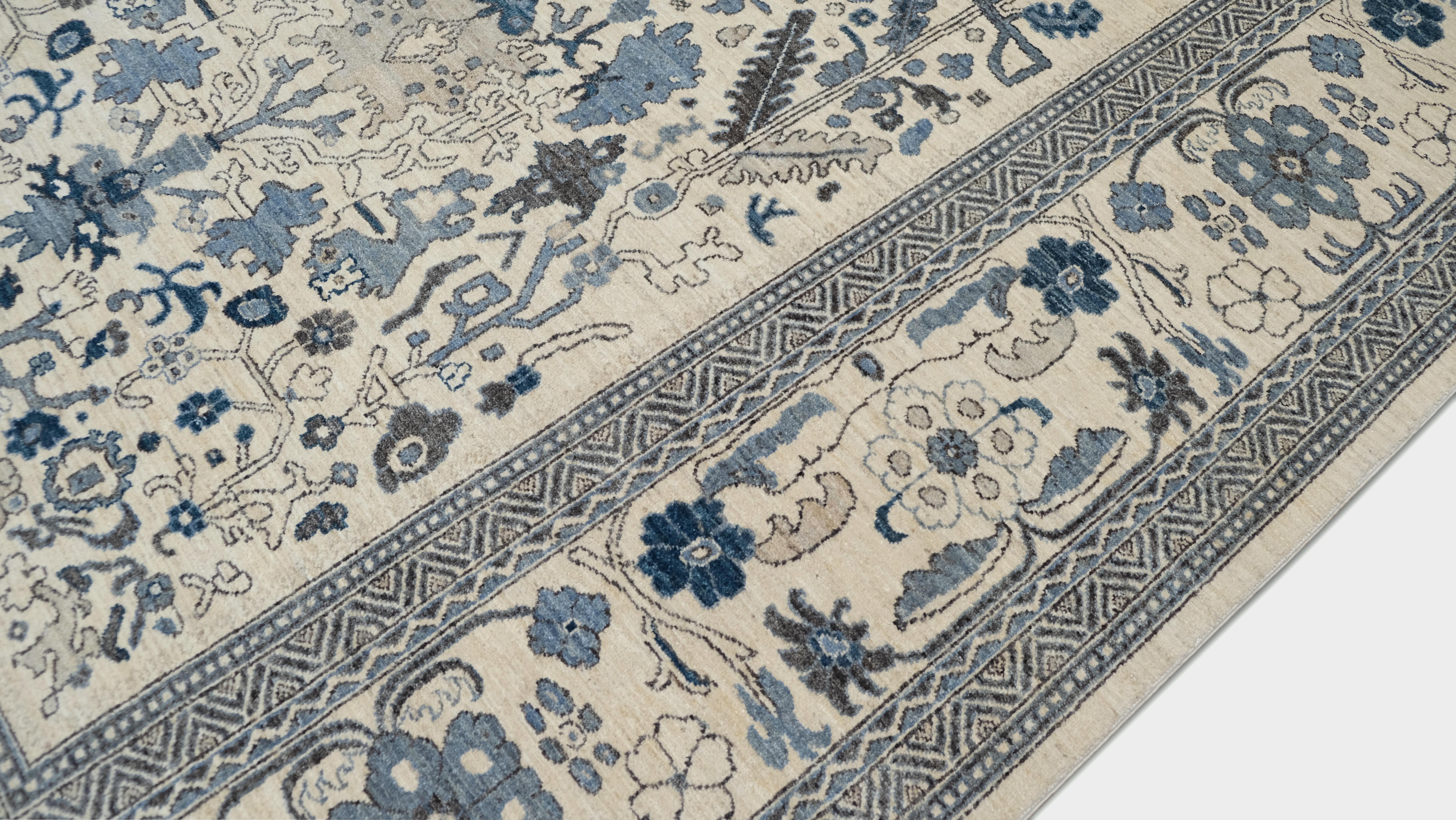 Dieser exquisite, handgeknüpfte Wollteppich zeigt ein elegantes florales und botanisches Motiv, das von traditioneller Handwerkskunst inspiriert ist. Das symmetrische Design zeigt verschlungene Ranken, Blüten und Blattwerk, die in tiefen Blau- und