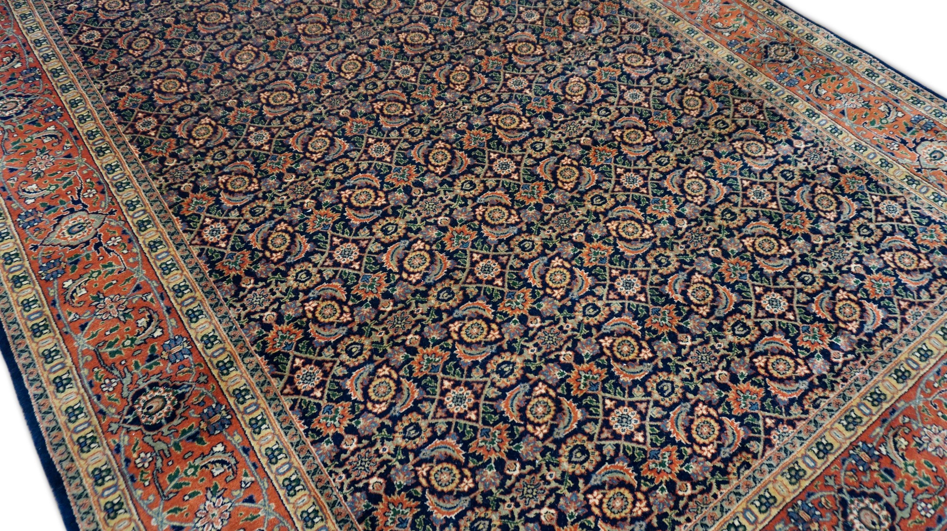 This exquisite hand-knotted wool rug is a superb representation of the Indo-Mahal tradition, showcasing masterful artistry and timeless influence. The rug features an intricate all-over rosette and Herati lattice design, densely packed across a deep