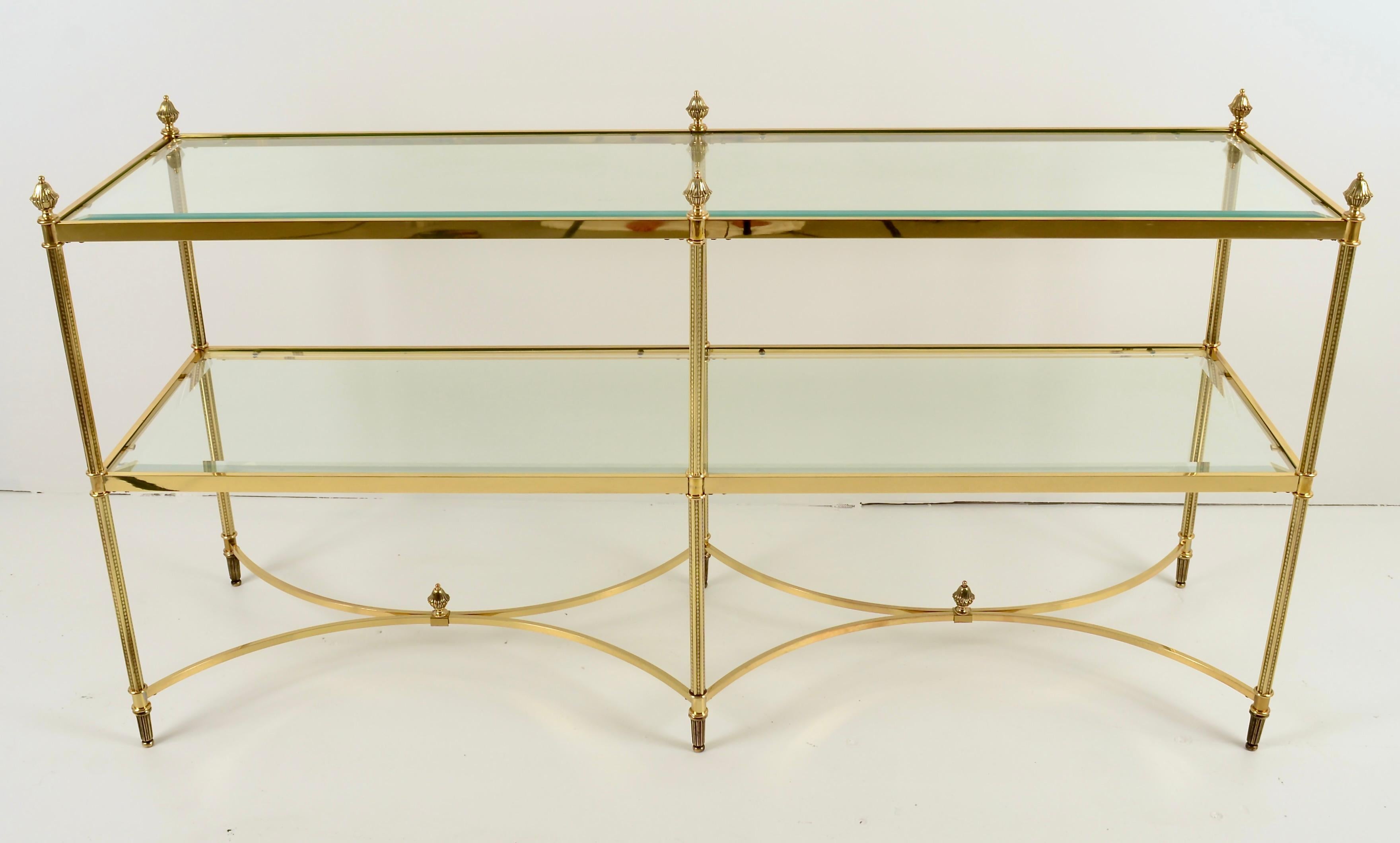 Polished brass sofa or console table with Neo-classical details and substantial, beveled glass shelves. Newly polished and lacquered. Total height is 30 inches to top of finials, table top is 28 inches.
