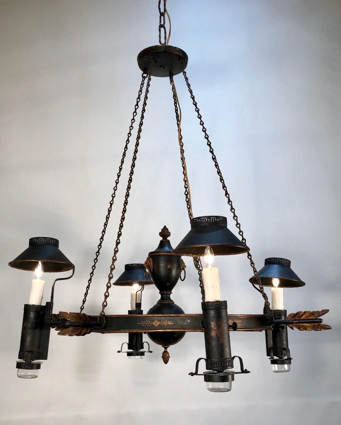 French neoclassical tole arrow chandelier decorated in dark green paint with original gilt stenciling has some of the finest tole details in the tole work. This Classic Regency form chandelier has four lights with tole smoke shades and was made in