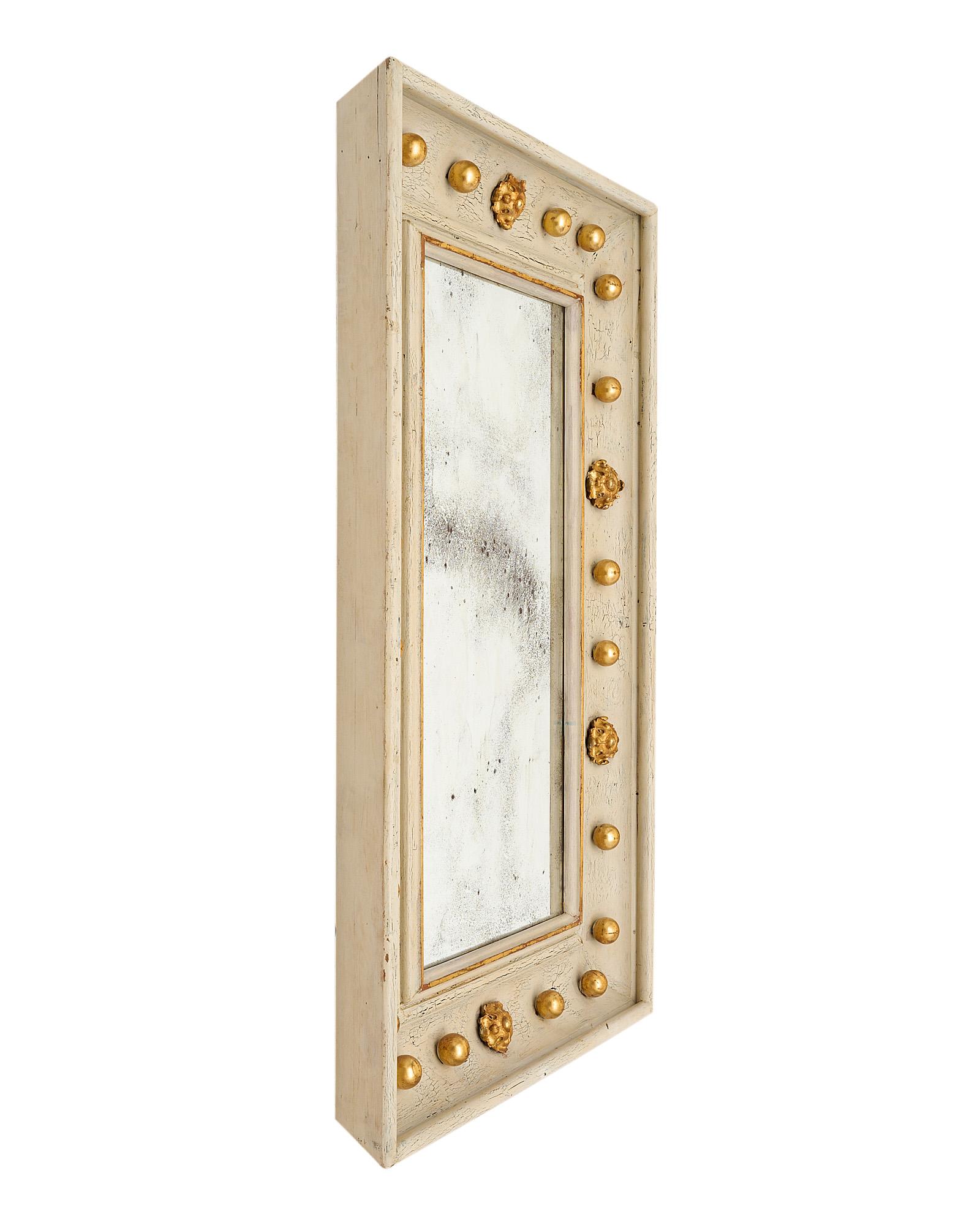 Mirror, French, in the neoclassical style and made of a hand-carved wooden frame with its original  “Trianon” gray paint and antique mirror. The highly decorative piece features 24 carat gold leafed spheres and Macarons.
