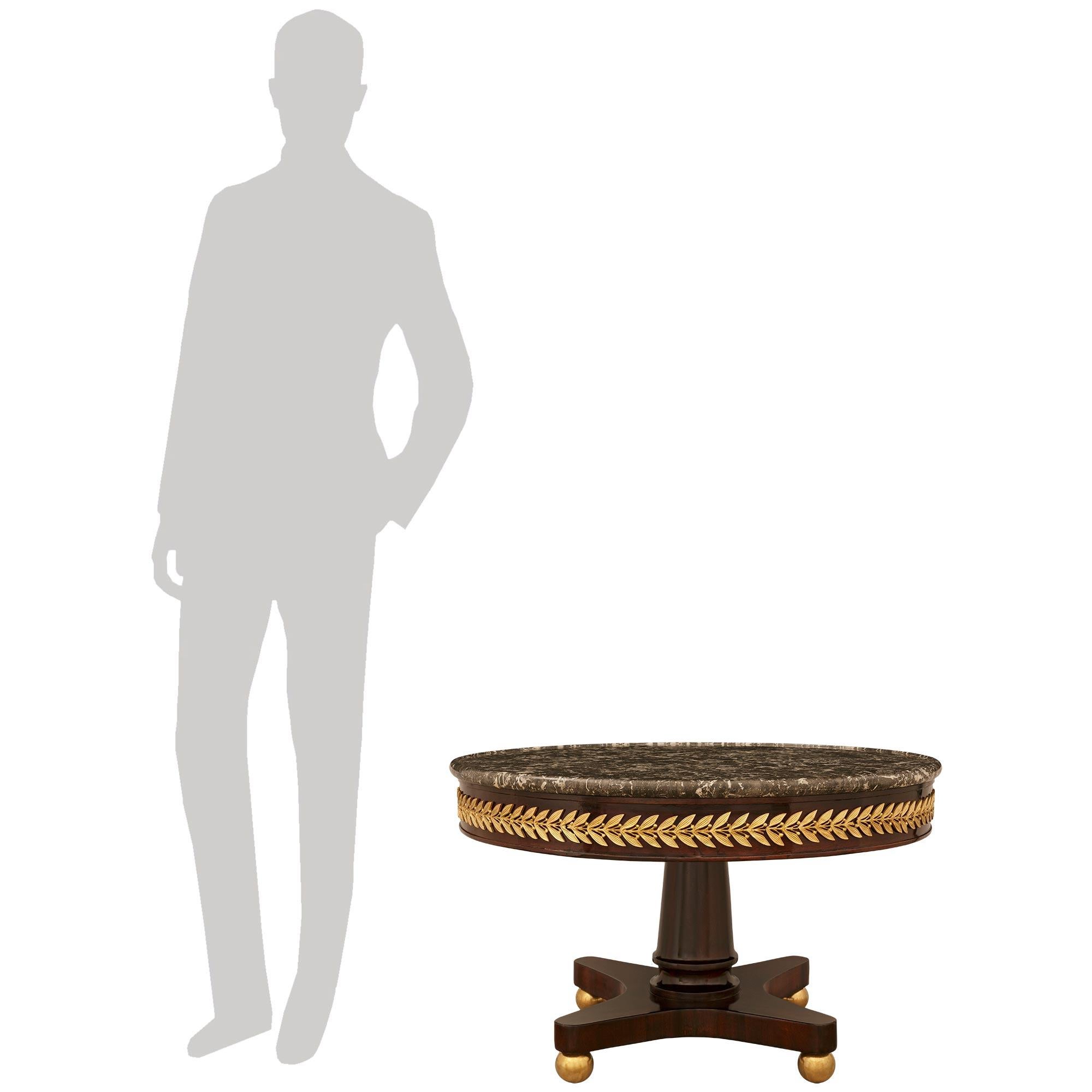 A handsome and most decorative French 19th century Neo-Classical st. Mahogany, Ormolu, and Gris St. Anne marble coffee table. This stunning table is raised on an X shaped Mahogany base above four impressive Ormolu ball feet. The central column