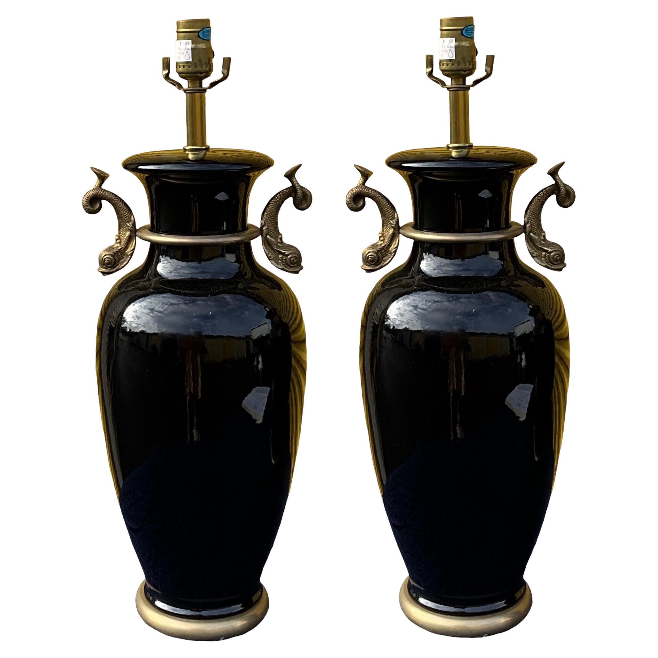 This is a pair of black neo-classical lamps with gilt dolphins by Frederick Cooper. They are in working order and very good condition.