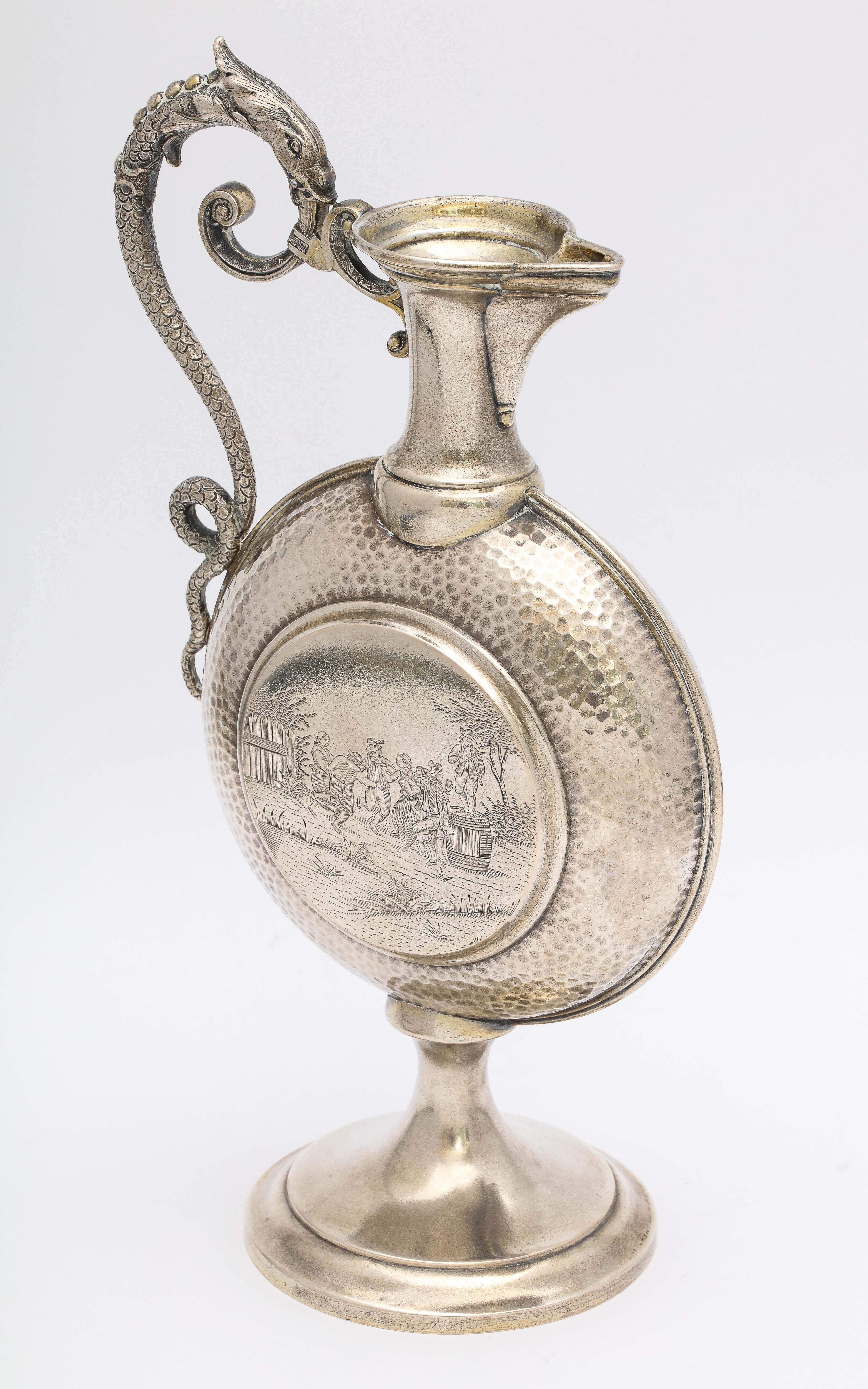 Neoclassical style, Continental Silver (.800) ewer/pitcher, Europe, circa 1910. Handle is in the form of a snake. Central portion of ewer is hand-hammered on both sides; each hammered part frames a scene. One side is a drinking scene; the other