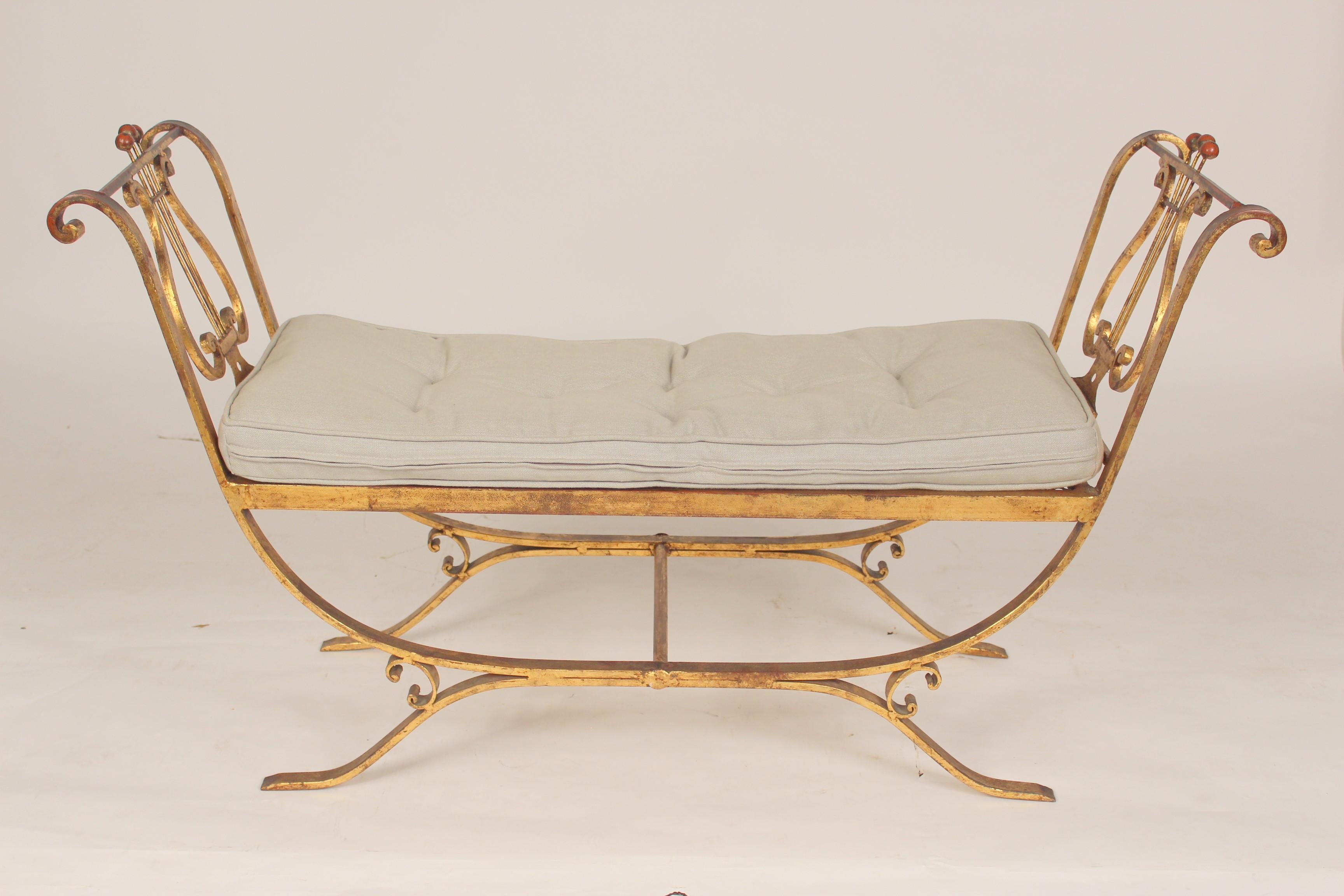 Neo classical style gilt iron bench, circa 1960's. Side arms with lyre shaped design and cushion with button and tuck upholstery.