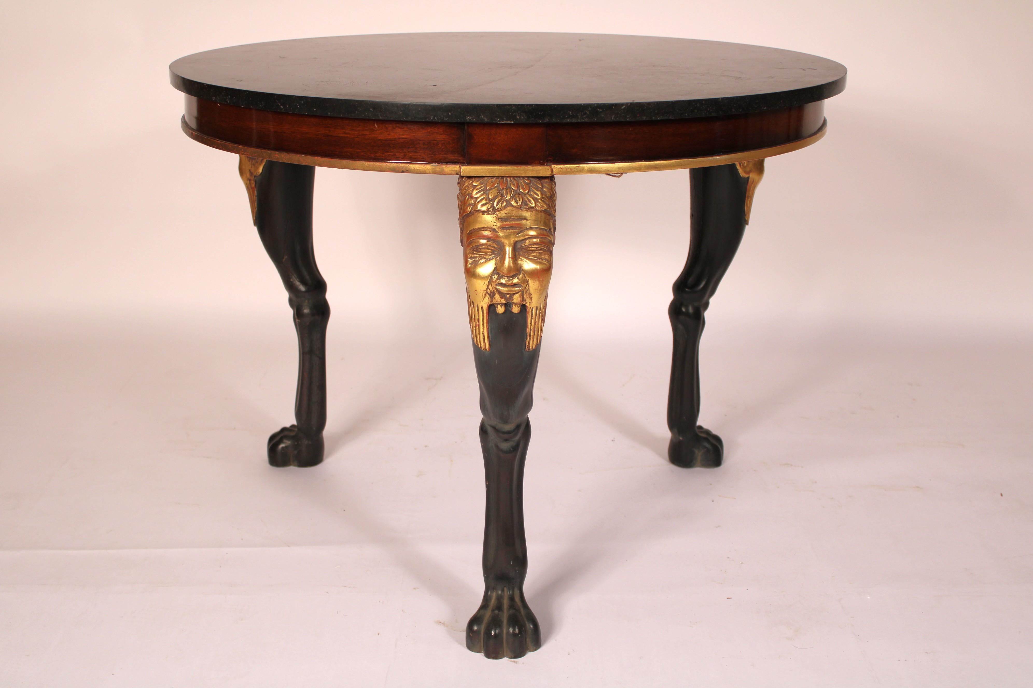 Neo classical style gilt wood and lacquer center table with a marble top, late 20th century. With a round marble top, mahogany frieze with gold leaf on lower border, 3 legs with carved gilt wood mask knees, animal form black lacquer legs ending in