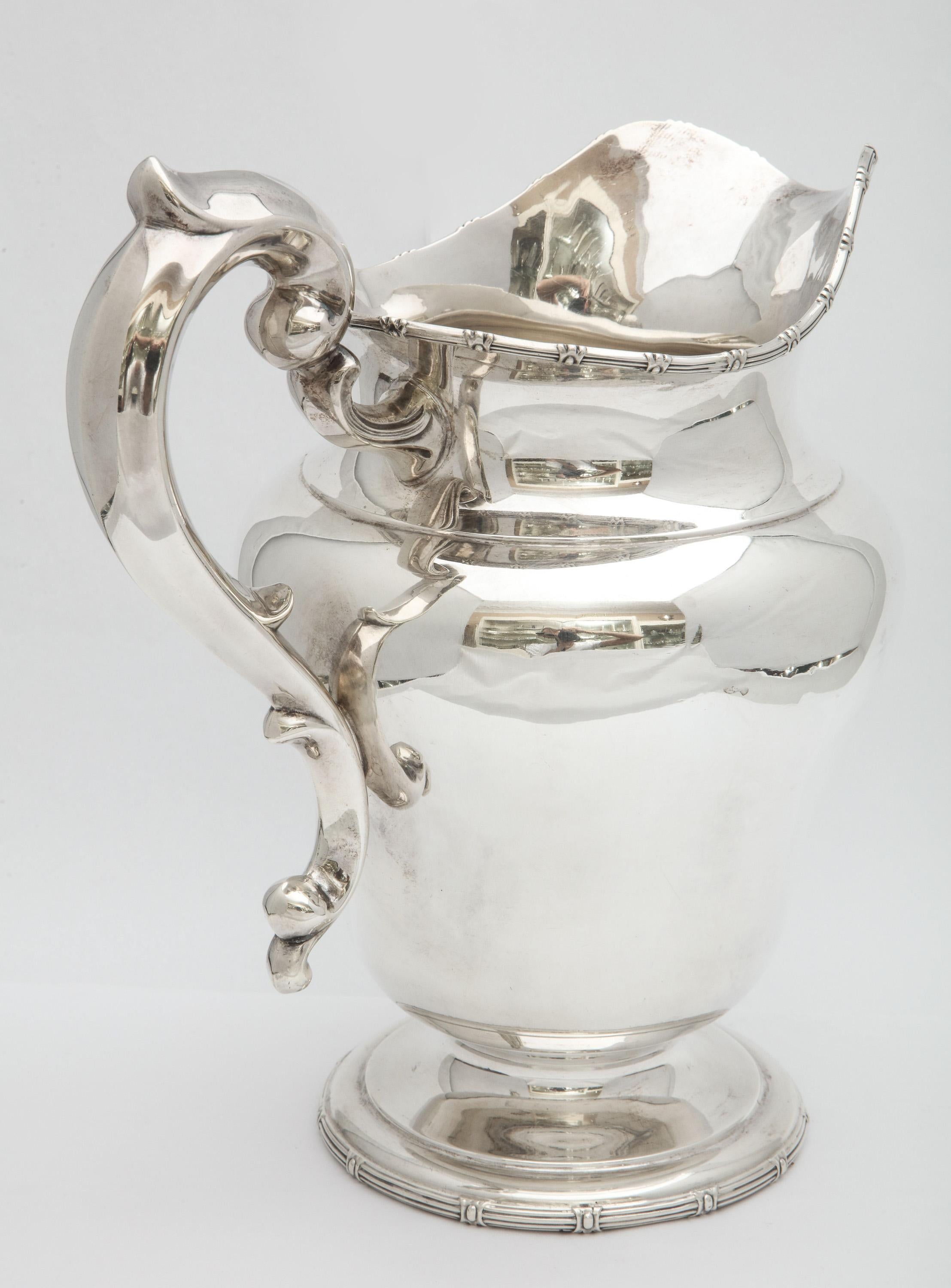 Neoclassical-style, sterling silver water pitcher, Frank Smith Silver Co., Gardner, Mass., circa 1905. Measures 10 1/4 inches high (at highest point) x 9 1/2 inches wide (from handle to handle x 7 inches diameter (at widest point). Lovely border on