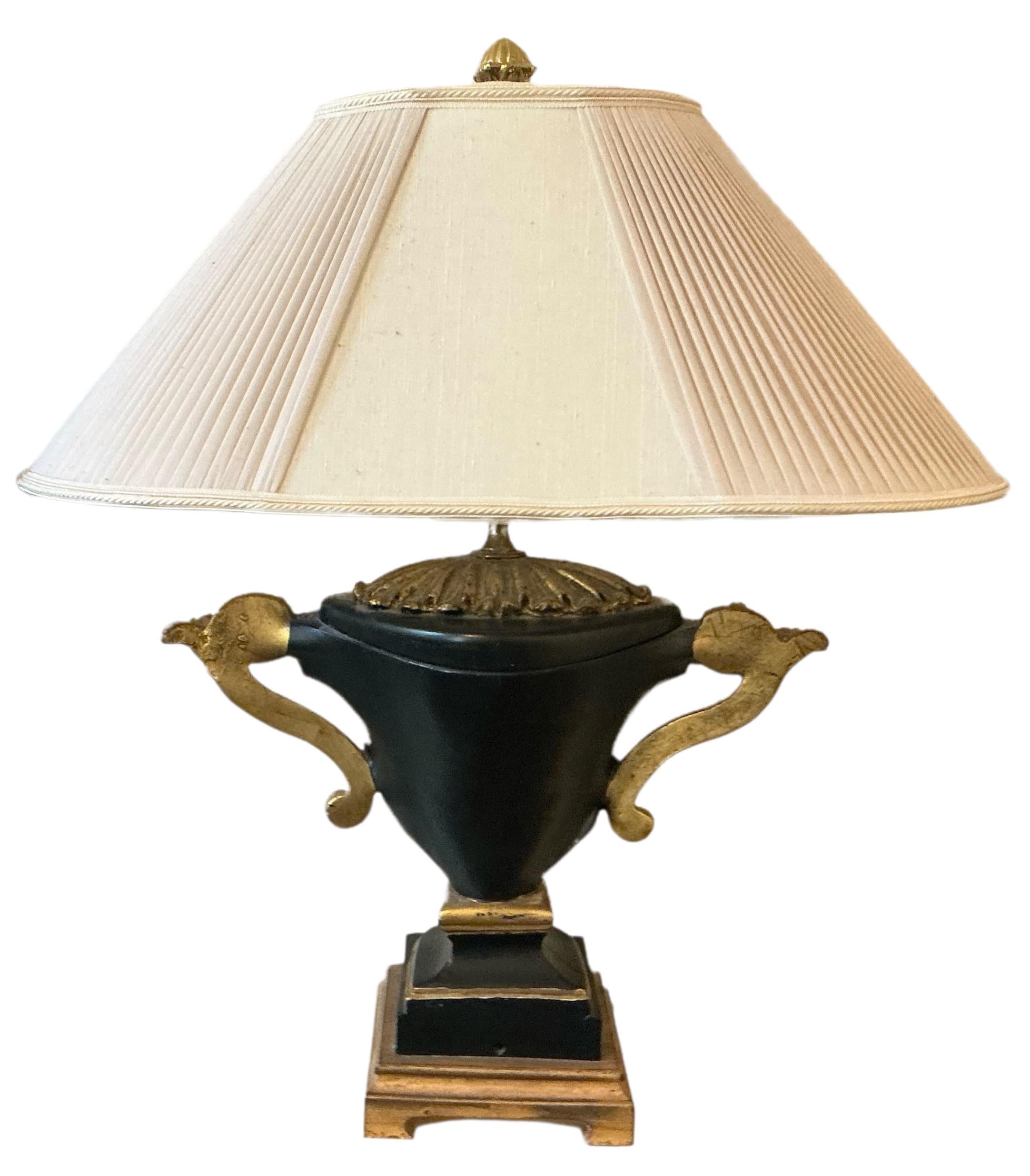 This is a neo-classical style lamp by Chelsea House . The gilded and ebonized urn is composition and is 16 inches handle to handle. The pleated shade is silk and in very good condition. It is marked.