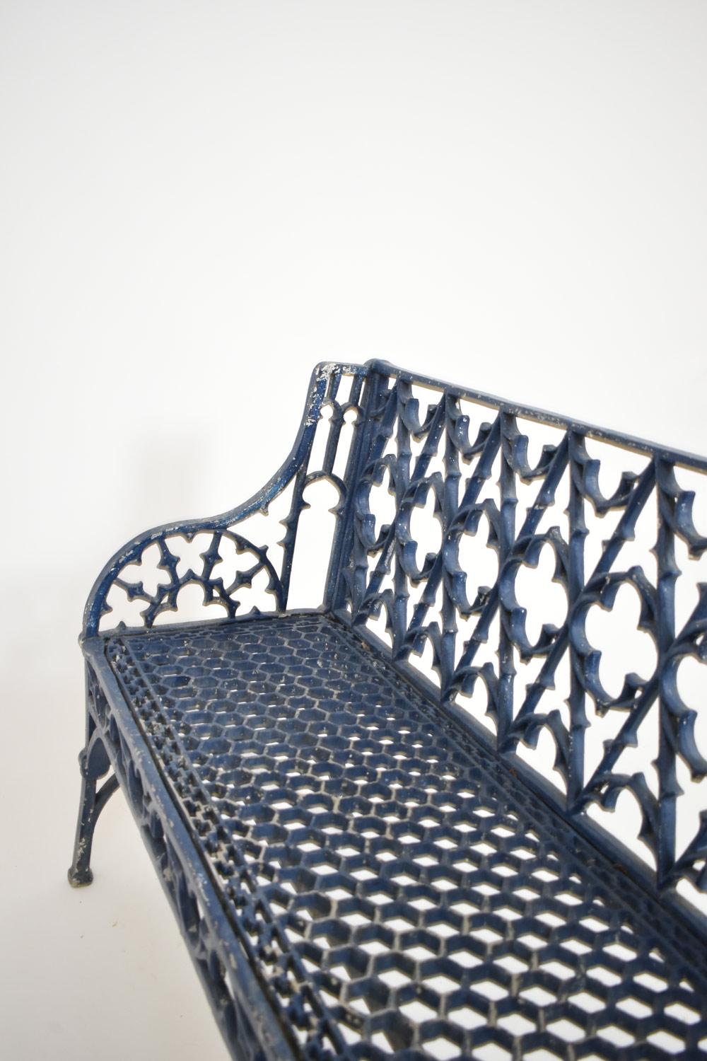 Neo-Gothic cast iron garden bench attributed to the English Coalbrookdale foundry. The backrest is decorated with Gothic tracings centered by quatrefoil motifs. The curved armrests contain demilune motifs. The seat is pierced with a honeycomb motif,