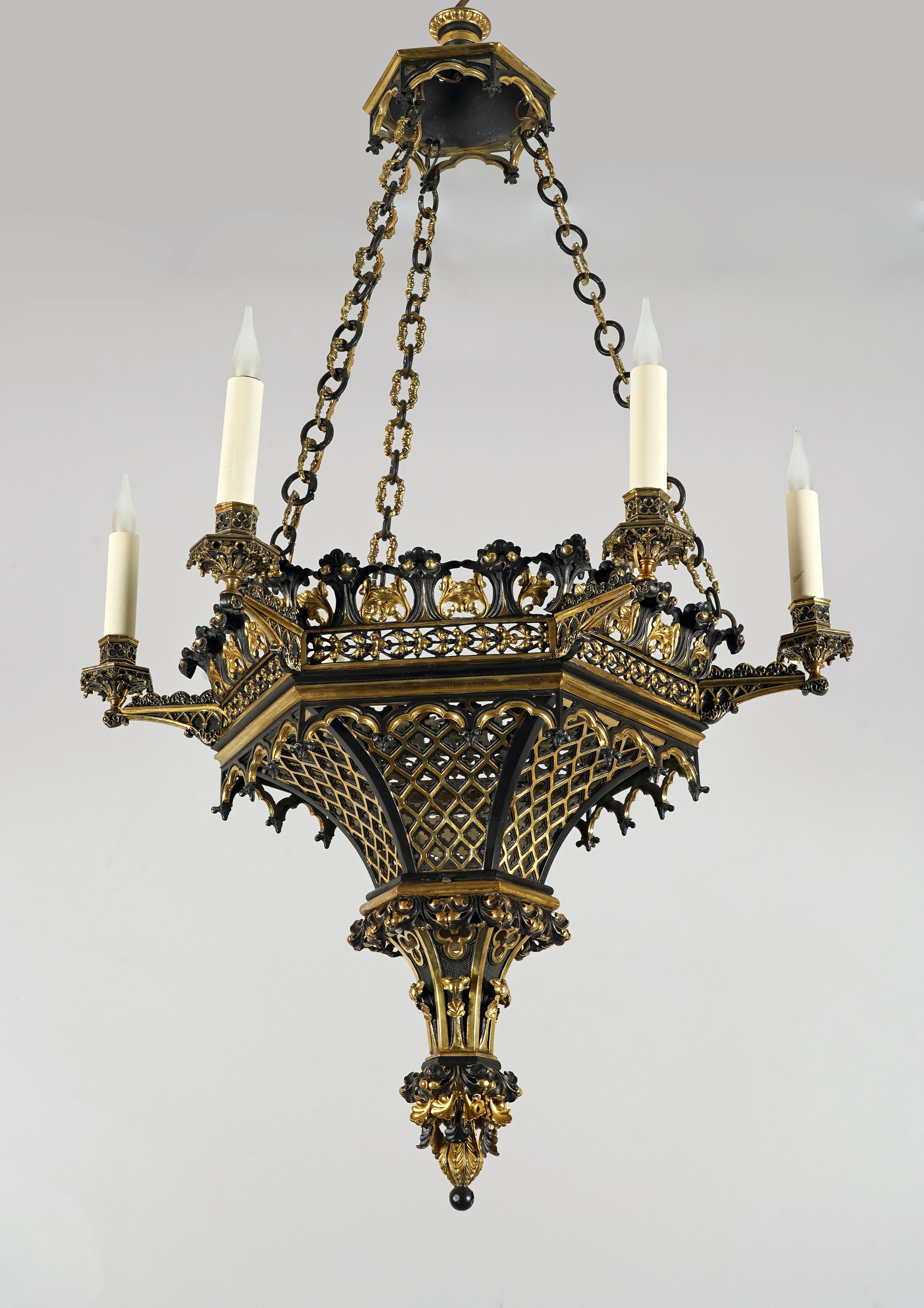 Bellissimo lampadario neogotico a sei luci, in bronzo patinato con riflessi dorati. Il fusto architettonico esagonale è trafitto da traverse quadrilobate, ispirate al repertorio decorativo dell'arte gotica, e termina con volute di fogliame.
I sei