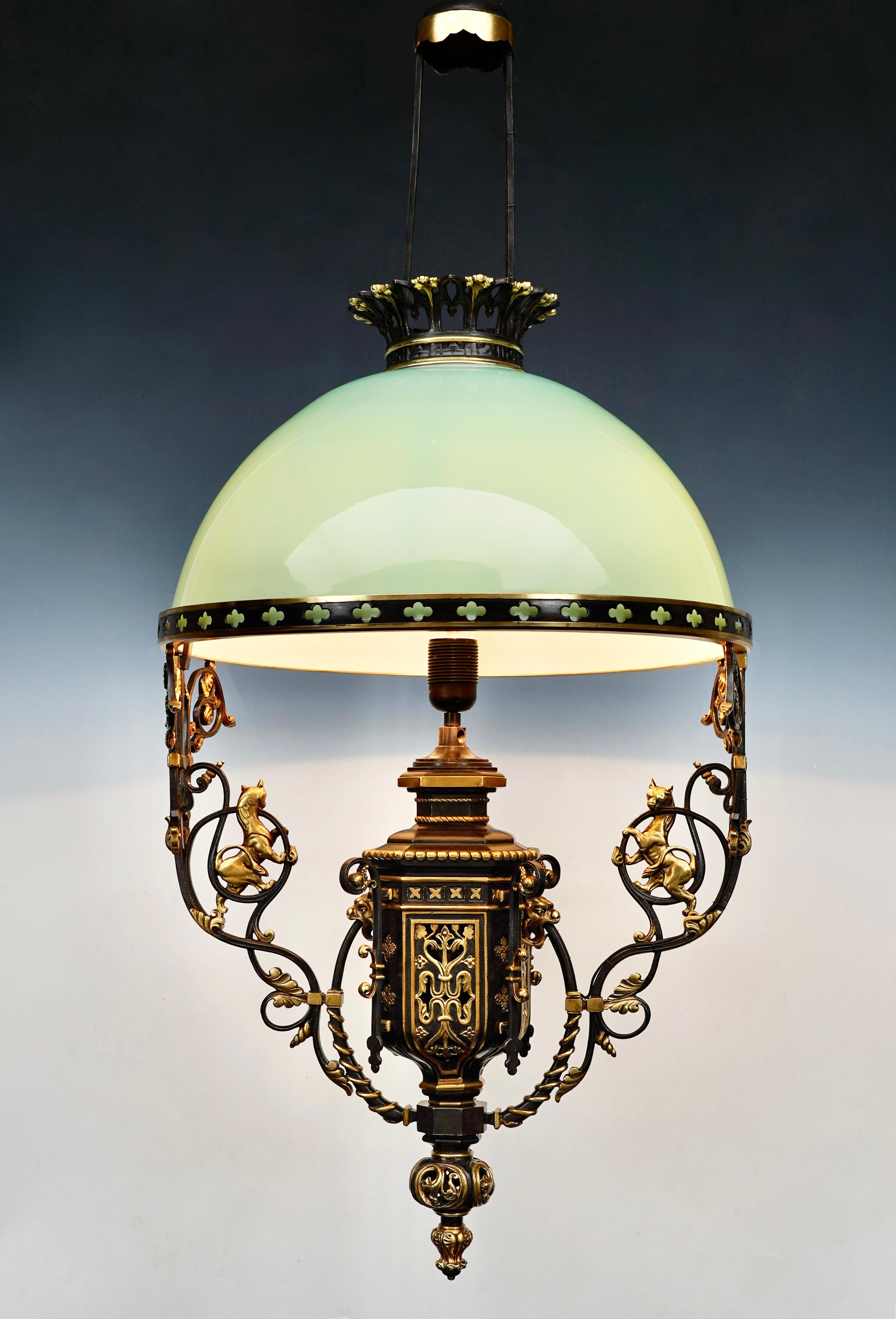 Beautiful neo-gothic chandelier in patinated bronze with gold highlights and water green opaline glass. The central shaft, decorated with cartridges in imitation of coats of arms, is decorated with gargoyle heads from which two branches of foliage