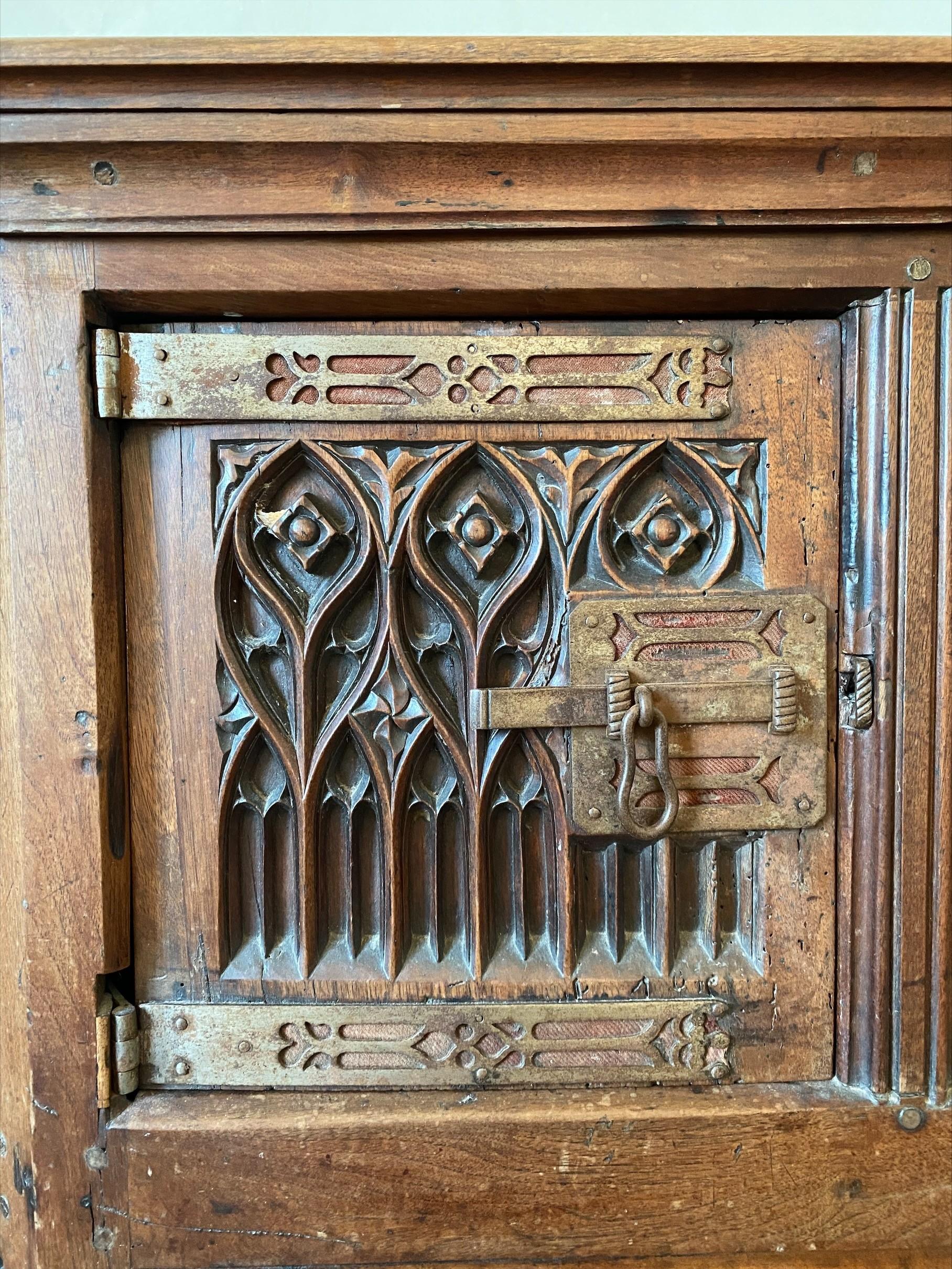 Beautiful neo-Gothic walnut sideboard from the end of the 19th century. The trim is made of metal, a type of wood widely used at the time. It has two doors with wrought iron locks, the panels are carved with typical gothic motifs such as ogives,
