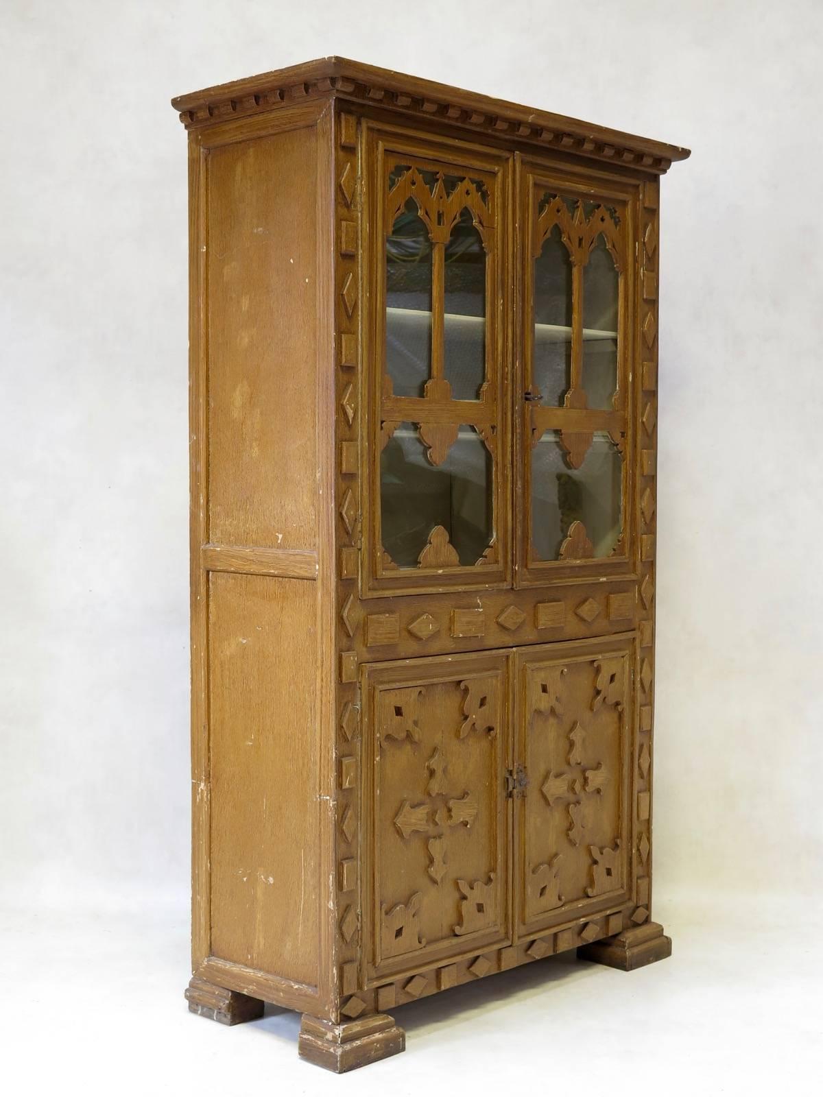 Delightful and unusual pinewood cabinet from the Jura region of France, painted with a faux-bois effect. The style has elements reminiscent of the Gothic aesthetic. The top section has glass panes, with a painted interior. The cornice is
