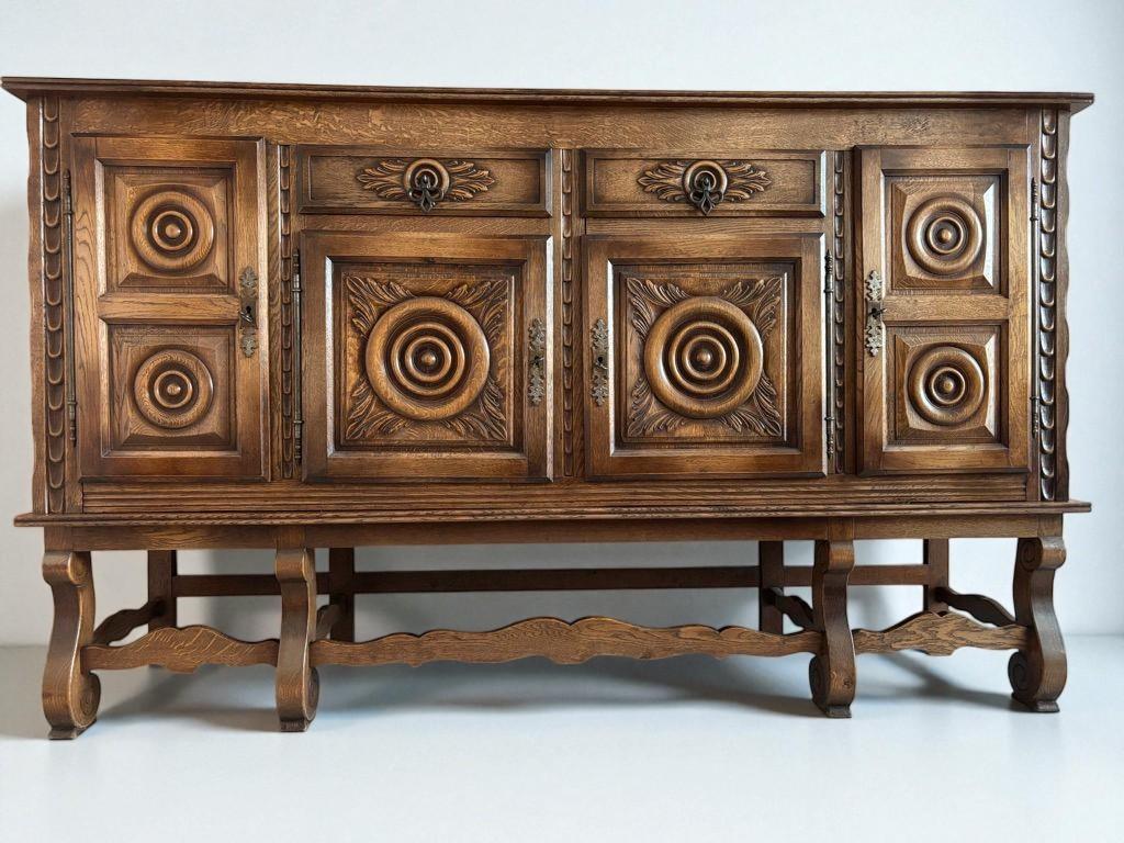 This stately sideboard showcases the richness of Neo-Renaissance design, characterized by symmetrical, sculptural ornamentation and robust proportions. Crafted from solid oak, the piece features deeply carved circular medallions framed by acanthus