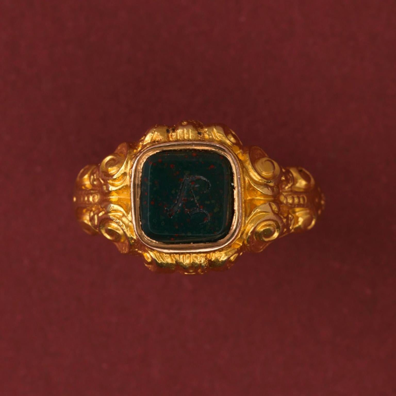 An 18 carat gold neo renaissance ring with a richly decorated shank with scrolls and leaves, a heliotrope or bloodstone intaglio of the initial A, at the back is a hidden compartment for a personal memento, France, circa 1880-1890.

weight: 9.85