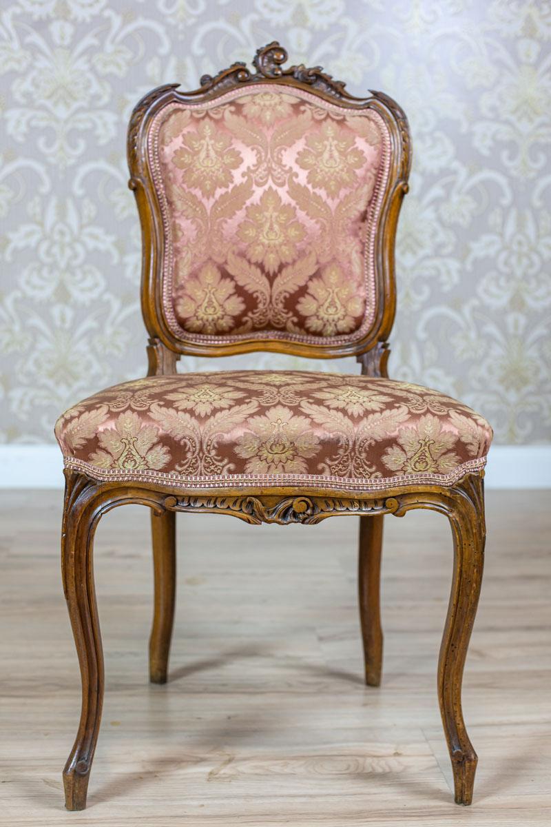 We present you a piece of furniture with a lightweight wooden frame and a softly upholstered seat and a backrest. All is from the Interwar Period.
The bent legs and backrest frame are decorated with carved patterns with fluting and the rocaille