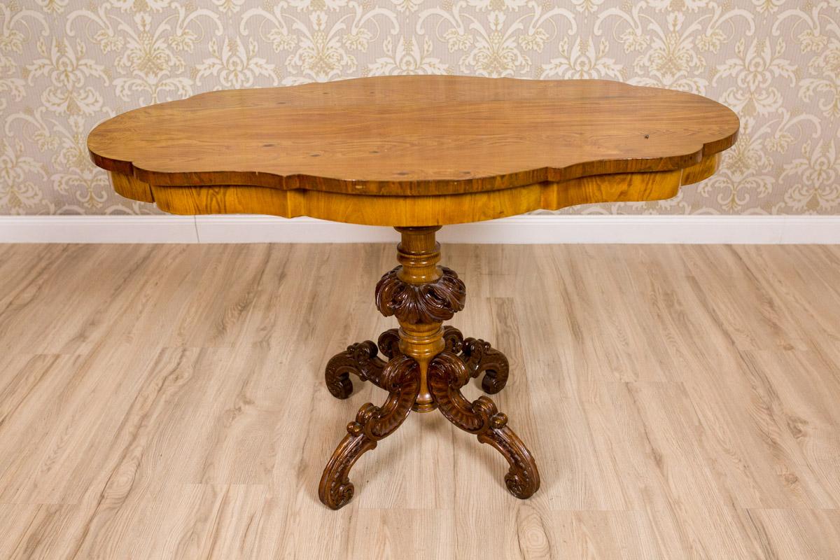 Ein Möbelstück im Stil des Neo-Rokoko. Dieser exquisite Tisch wurde aus Kirsch- und Mahagoniholz gefertigt.
Die Tischplatte ist profiliert, darunter befindet sich eine gleichförmige Leiste, die auf einem gedrechselten Sockel mit vier Beinen