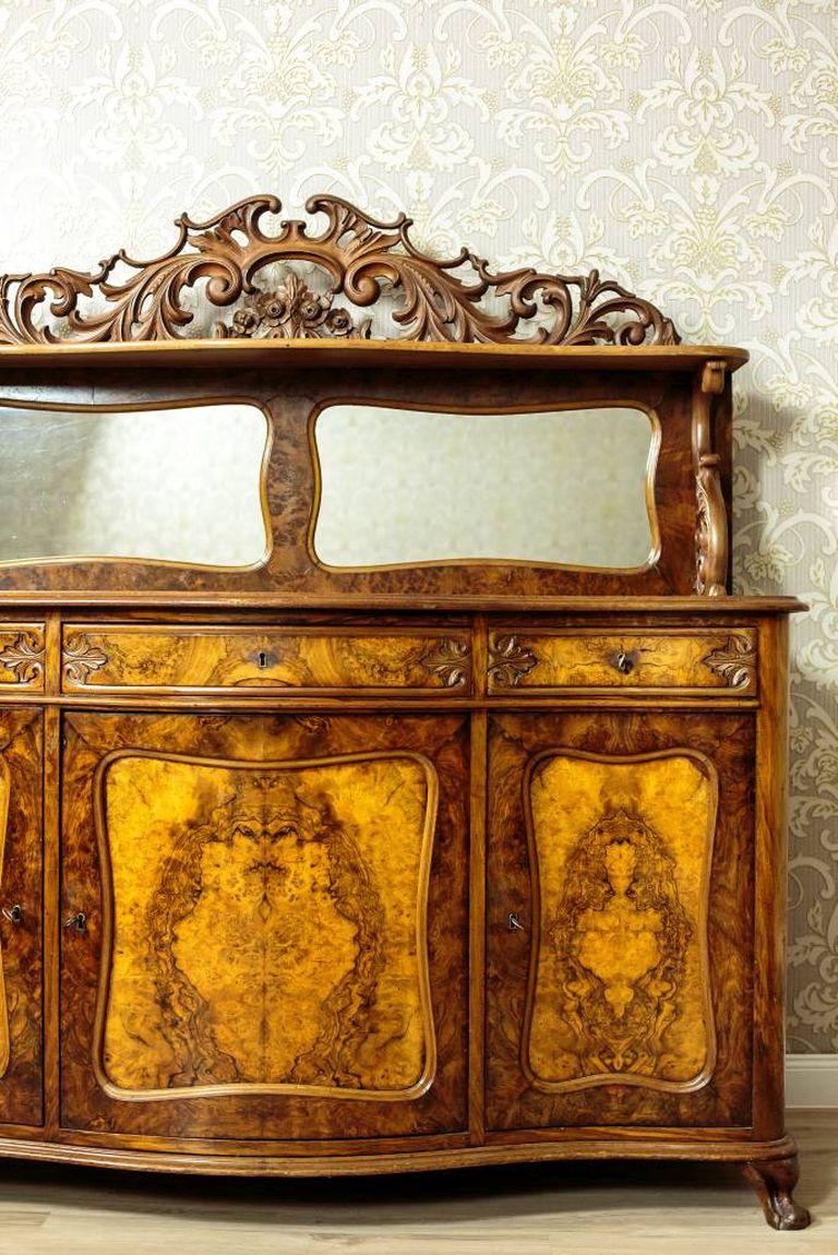 We present you this exquisite Neo-Rococo sideboard/buffet.
This piece of furniture is made in wood and walnut veneer. The fronts have been veneered with burl.
The cupboard is composed of two parts: a three-door base and an upper section with