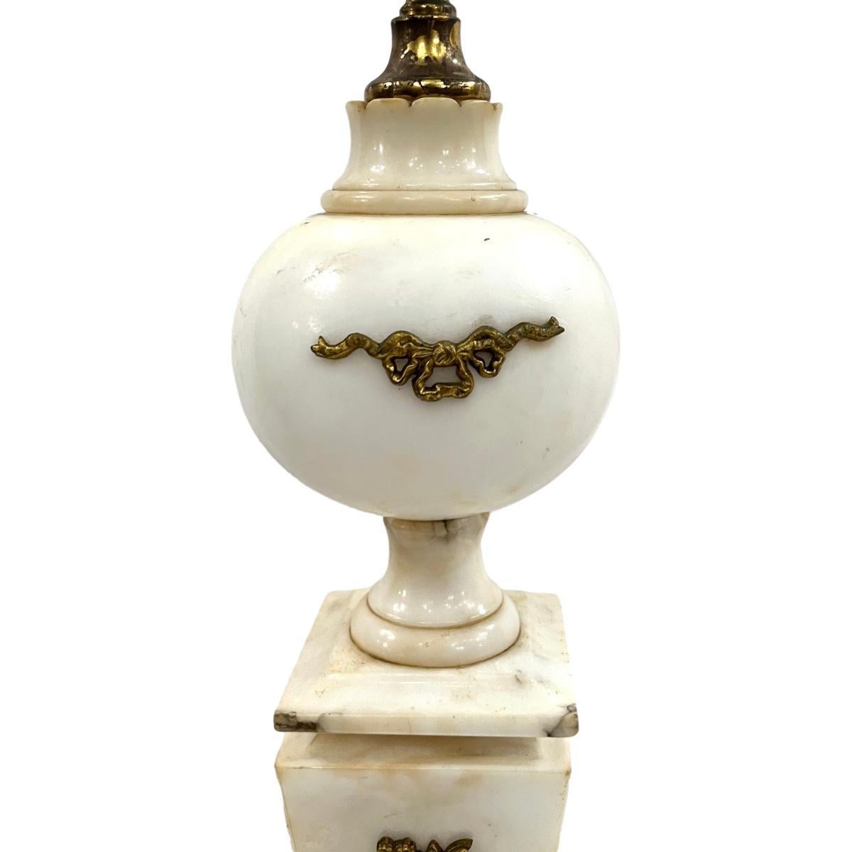 Pareja de lámparas de sobremesa de alabastro tallado de estilo neoclásico francés de hacia 1920, con decoraciones aplicadas de bronce dorado.

Medidas:
Altura del cuerpo: 18
Altura hasta el apoyo de la sombrilla: 27
Base Cuadrada de 5