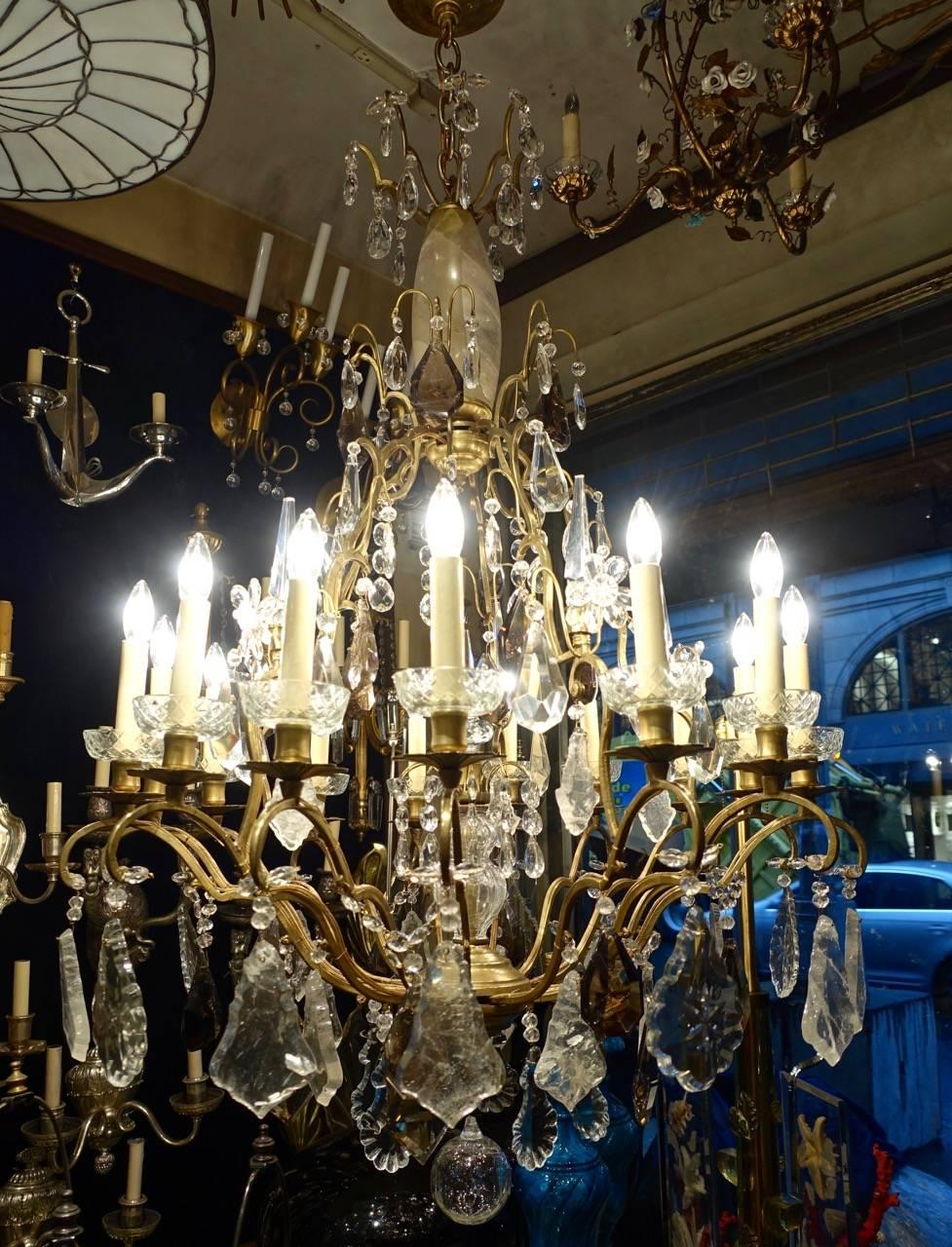 A circa 1900 French neoclassic style gilt bronze chandelier with 15 lights, with rock crystal and smoke color quartz pendants.

Measurements:
Height: 45