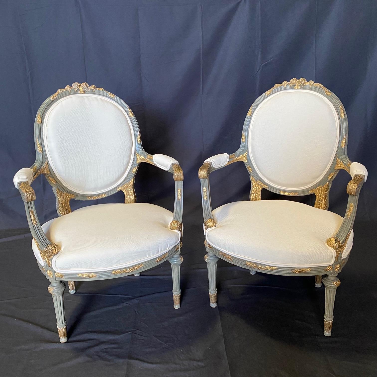 A French neoclassical pair of carved wood blue grey painted armchairs or fauteuils from the early 19th century with high end neutral new upholstery and having cameo round backs with round softly curved wooden top rail that slopes down from the