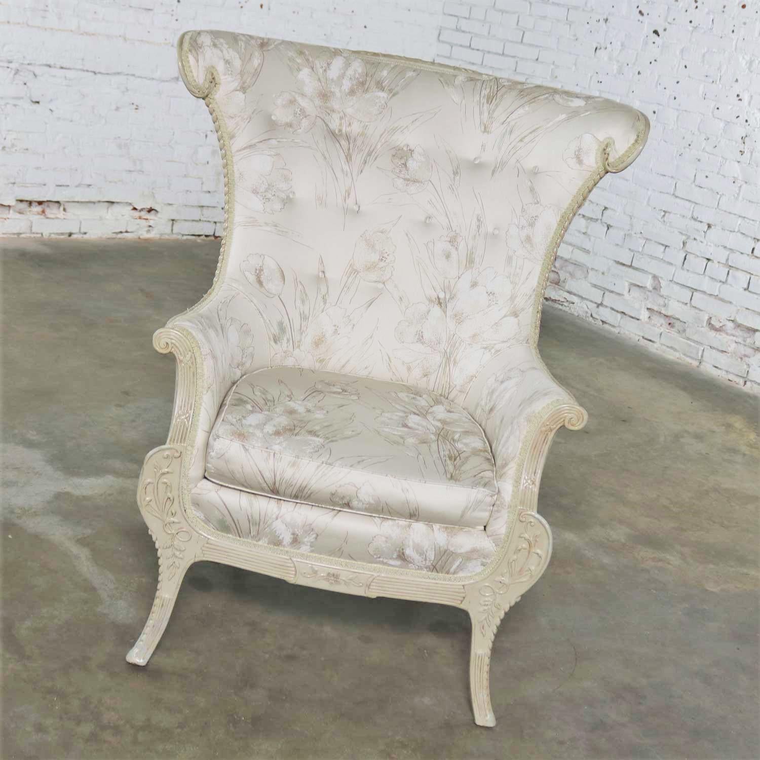 Gorgeous large wingback lounge chair in a neoclassic French style with an antique white finish on the carved wood frame and an antique white and taupe upholstery fabric. It is in wonderful vintage condition and if you like the fabric, ready to use.