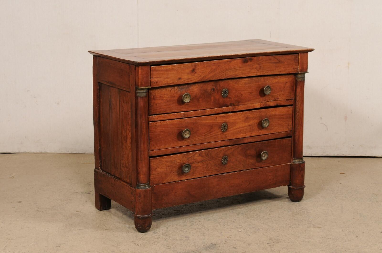 A French Neoclassical four drawer commode, with its original metal hardware and accents, from the 19th century. This antique chest from France features a rectangular-shaped top, which slightly overhangs the case which houses four drawers (upper