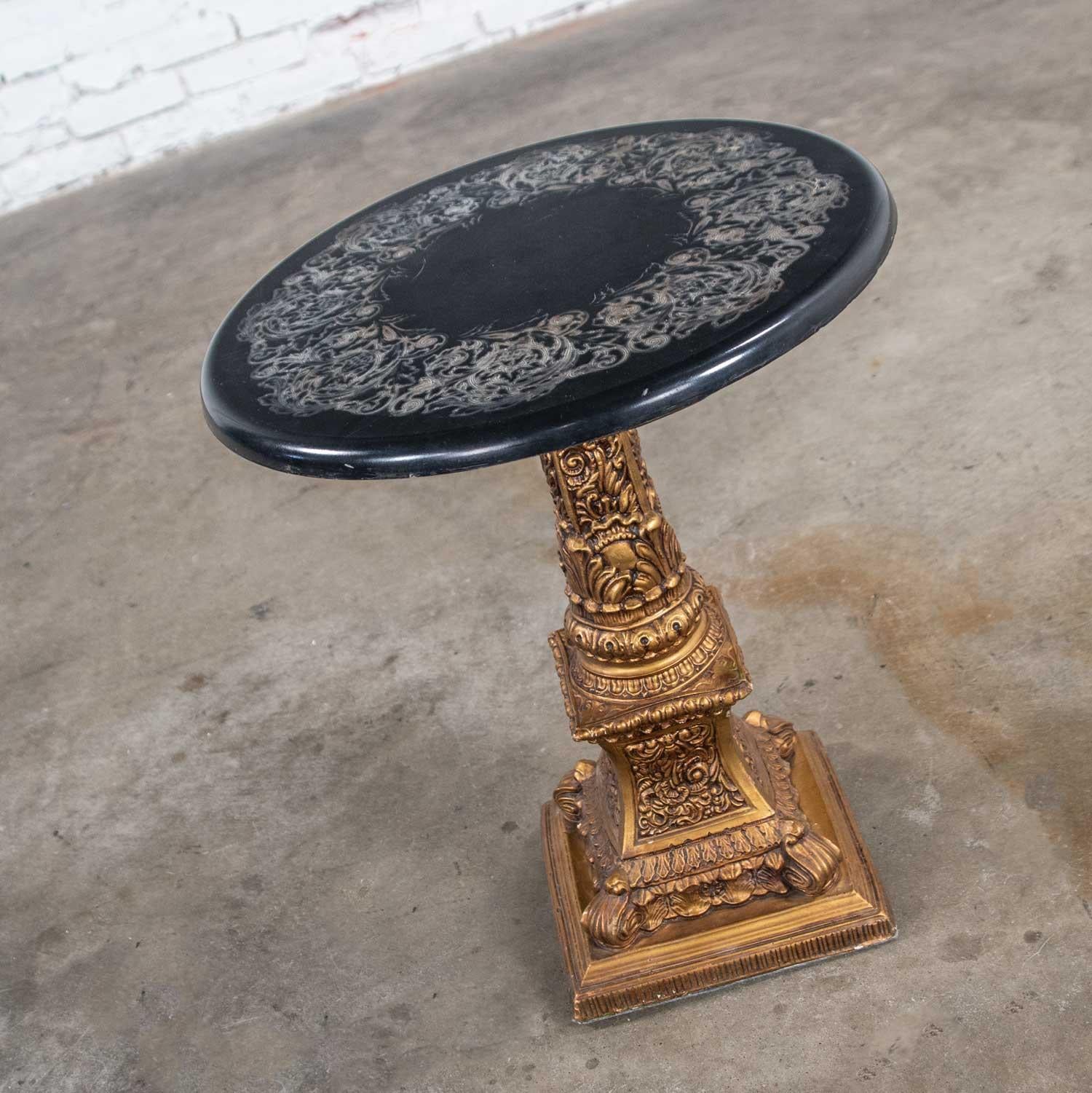 Wunderschöner runder Beistelltisch oder Beistelltisch im Neoklassizismus oder Hollywood Regency, bestehend aus einem vergoldeten Gipssockel und einer runden schwarzen Platte mit geschnitztem oder geätztem Design. Es ist in wunderbarem