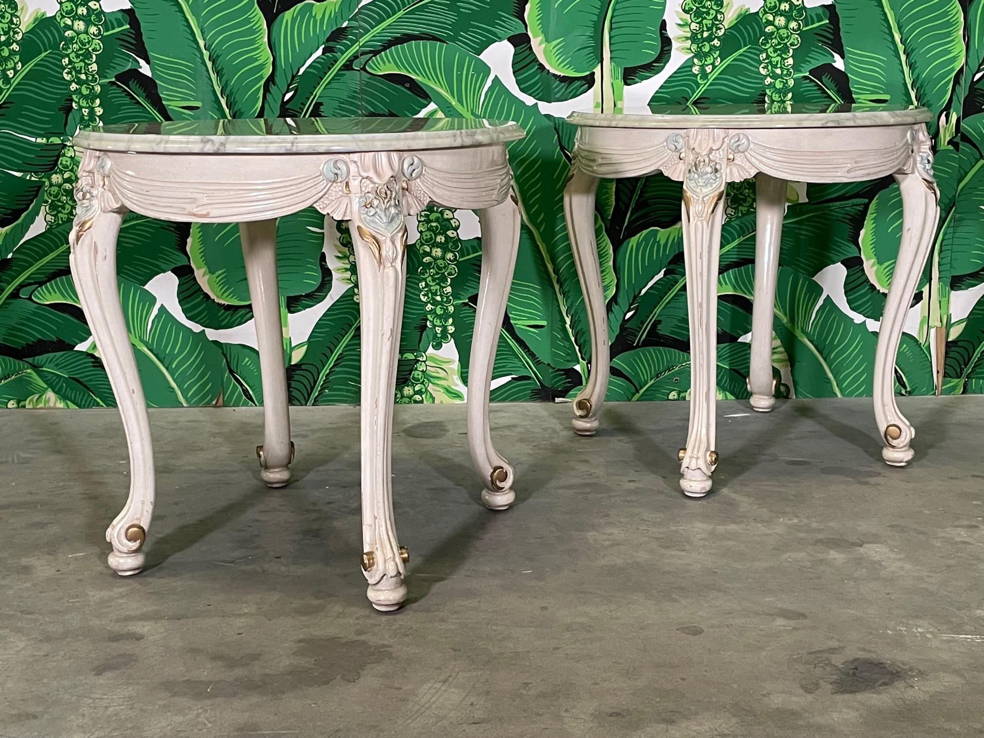 Pair of mid century Neoclassical style side tables feature a marble top and cabriole legs. Hand carved detailing in a draped fabric motif with hand painted accents. Good condition with minor imperfections consistent with age. May exhibit scuffs,