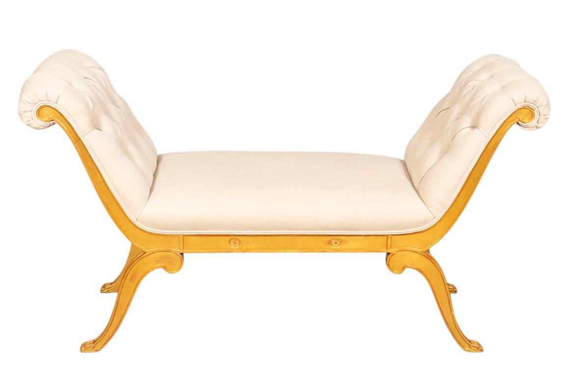With arched scrolled arms and rectangular seat in tufted creme colored upholstery and splayed legs with paw feet.