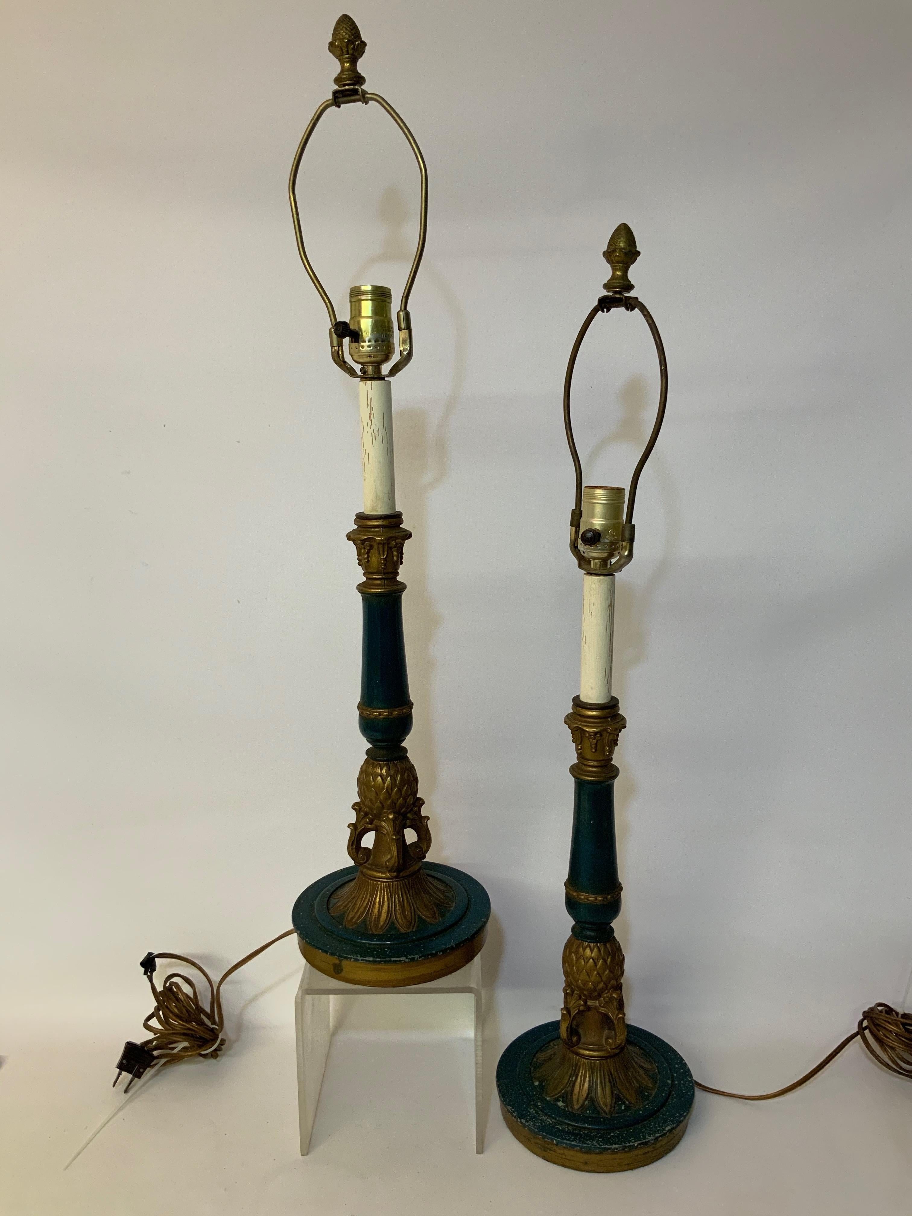 Cast metal foliate and scroll pineapple lamps with white wood toppers ending with a metal acorn finial. Dark green and parcel-gilt, circa 1960-1970. Good condition with original wiring. Harps included. No shades. Overall wear from age and