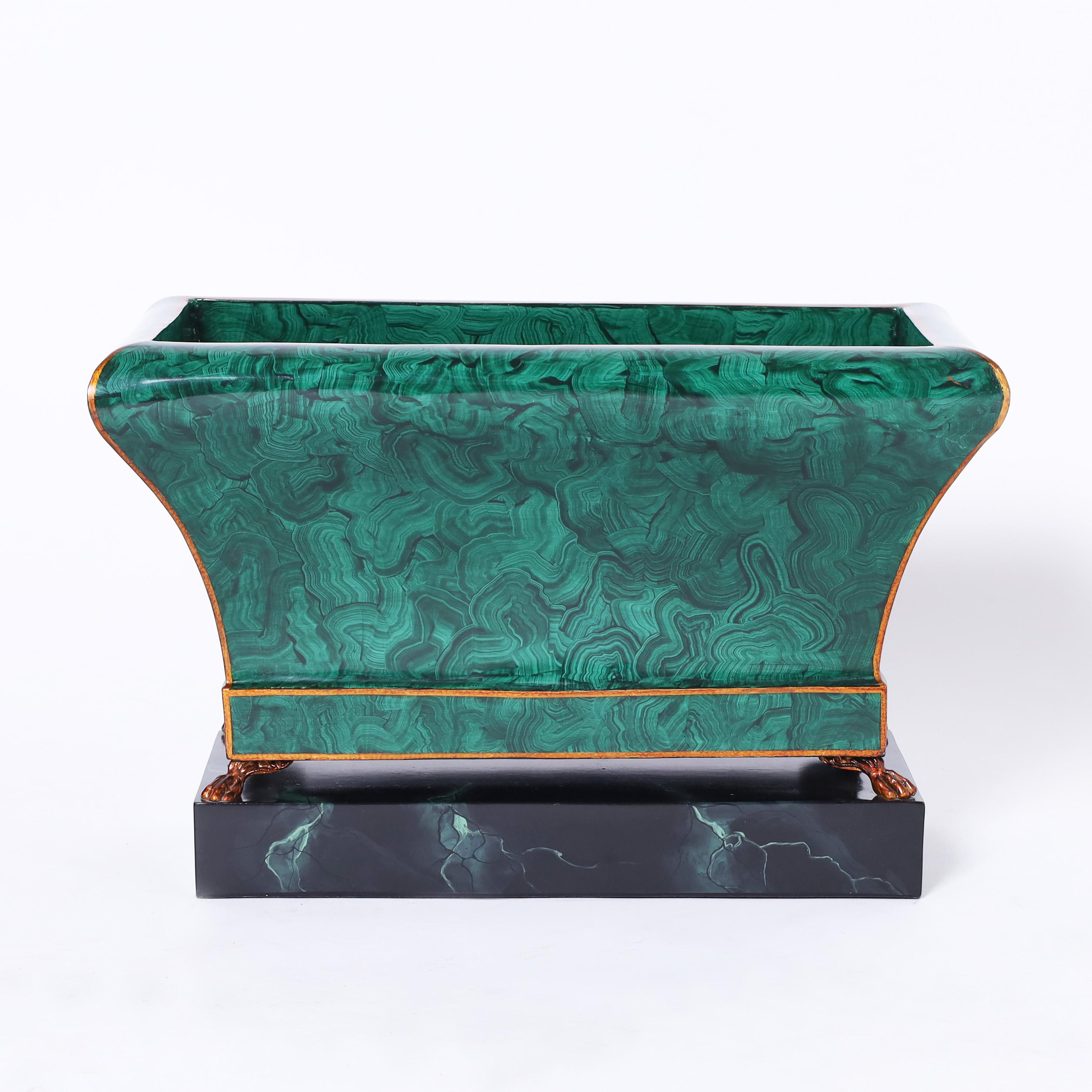 Chic vintage classical jardiniere handcrafted in metal with a faux malachite finish on four paw feet over a faux marble tole plinth. Signed Maitland Smith on the bottom.