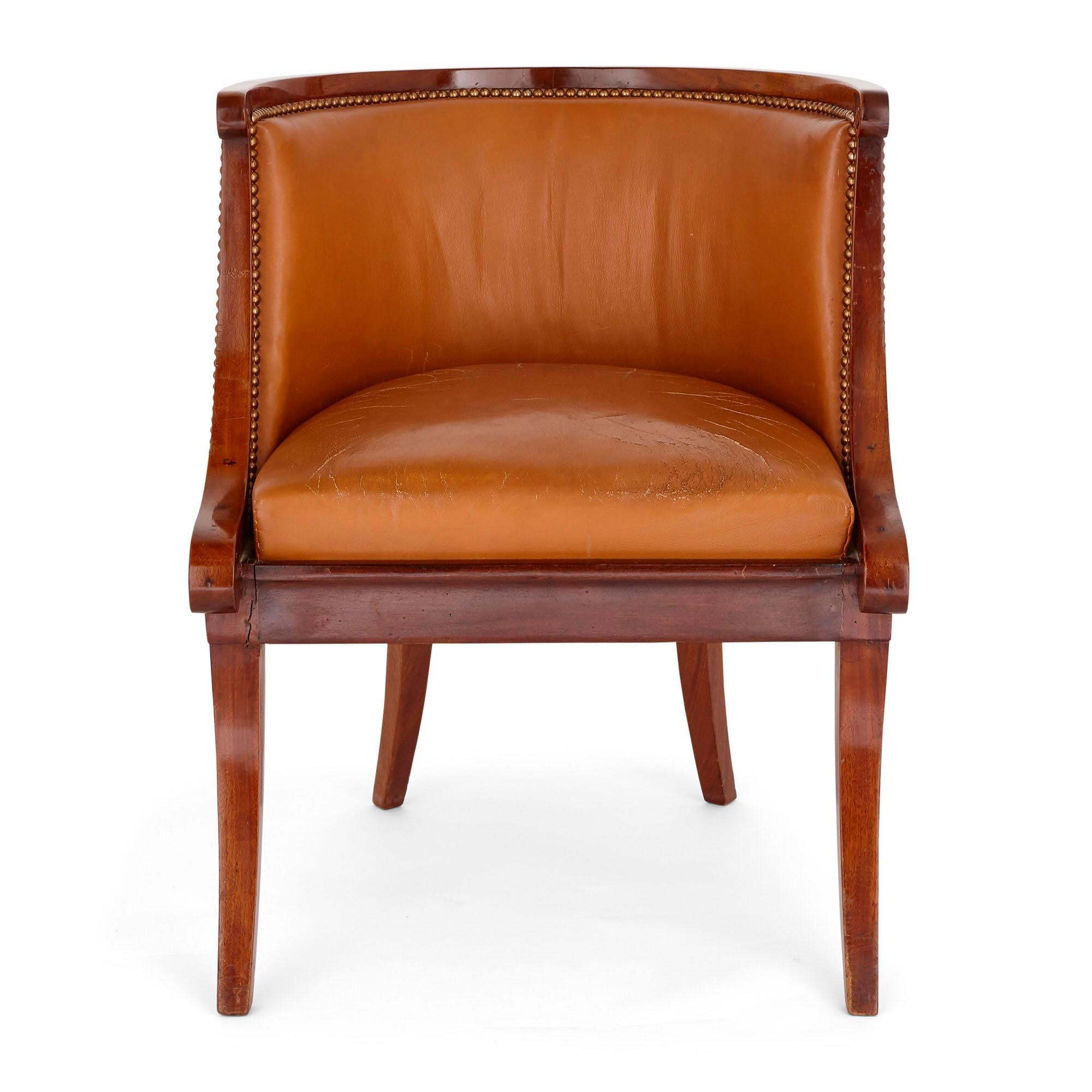 This French wood and leather armchair, which dates from the period of Louis XVI, is neoclassical in design and styling. The construction is elegant and refined: the chair stands on four swept legs, is upholstered with orange-tan leather on the