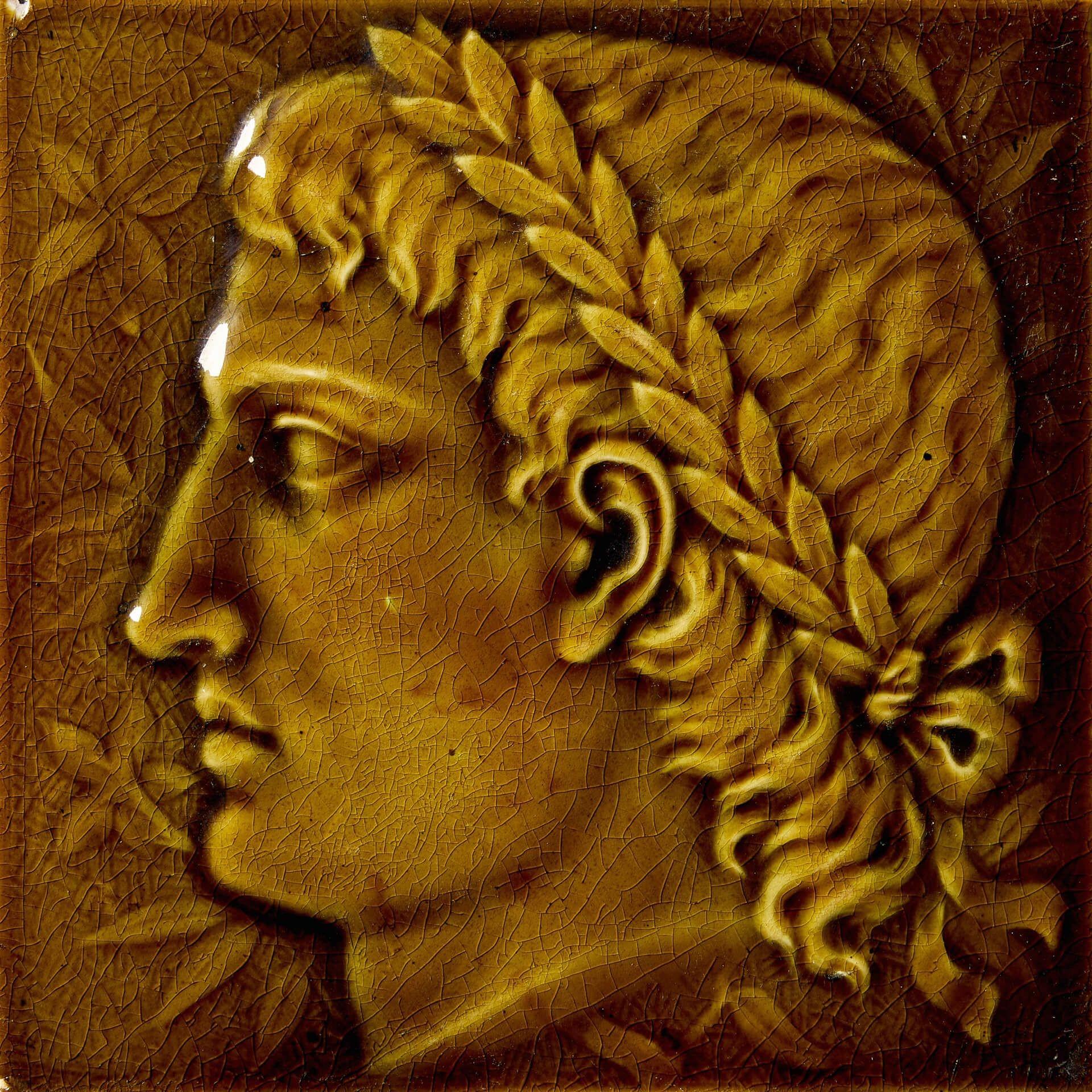 Carreau de faïence émaillée brun olive du XIXe siècle, pressé par la poussière, représentant un portrait de profil d'un personnage néoclassique avec une coiffe en couronne de laurier sur fond de feuillage.

La beauté de cette tuile est telle que le