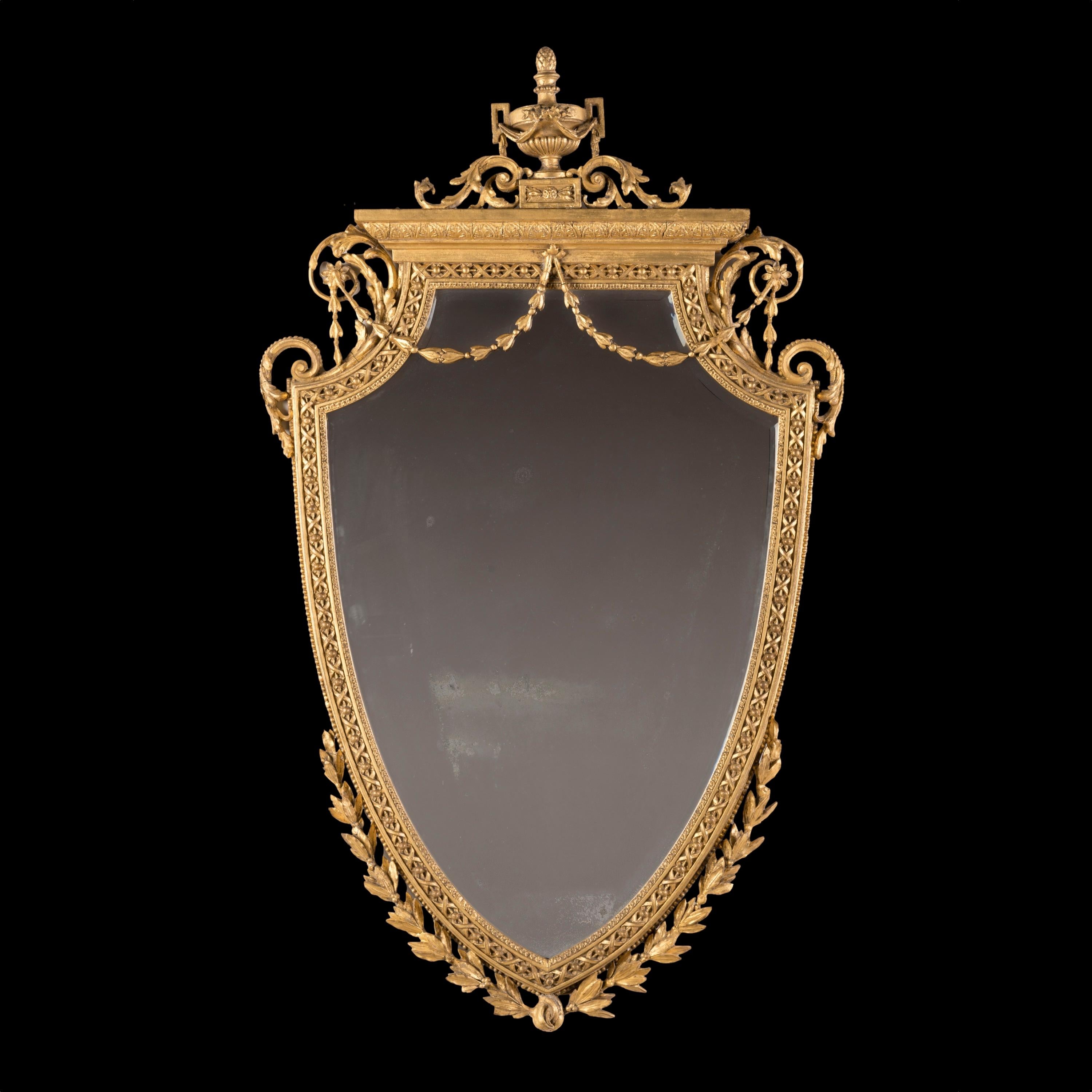 Un espejo neoclásico de madera dorada

Tallada en madera y elaborada con detalles de gesso, la placa de espejo en forma de escudo con borde biselado y alojada en un marco dorado, con intrincados diseños de roleos y elementos decorativos que incluyen