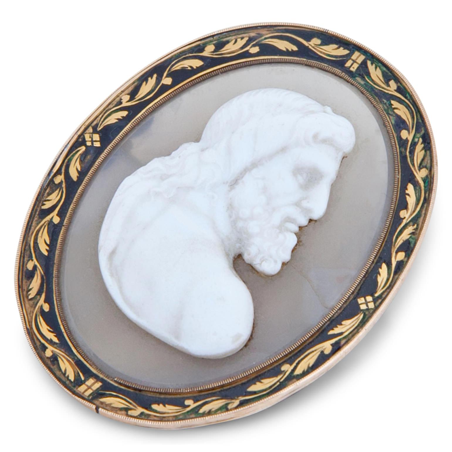 Small oval cameo broche in a gold frame out of Agate, depicting the profile of a bearded god. The brooch is fastened with a needle.